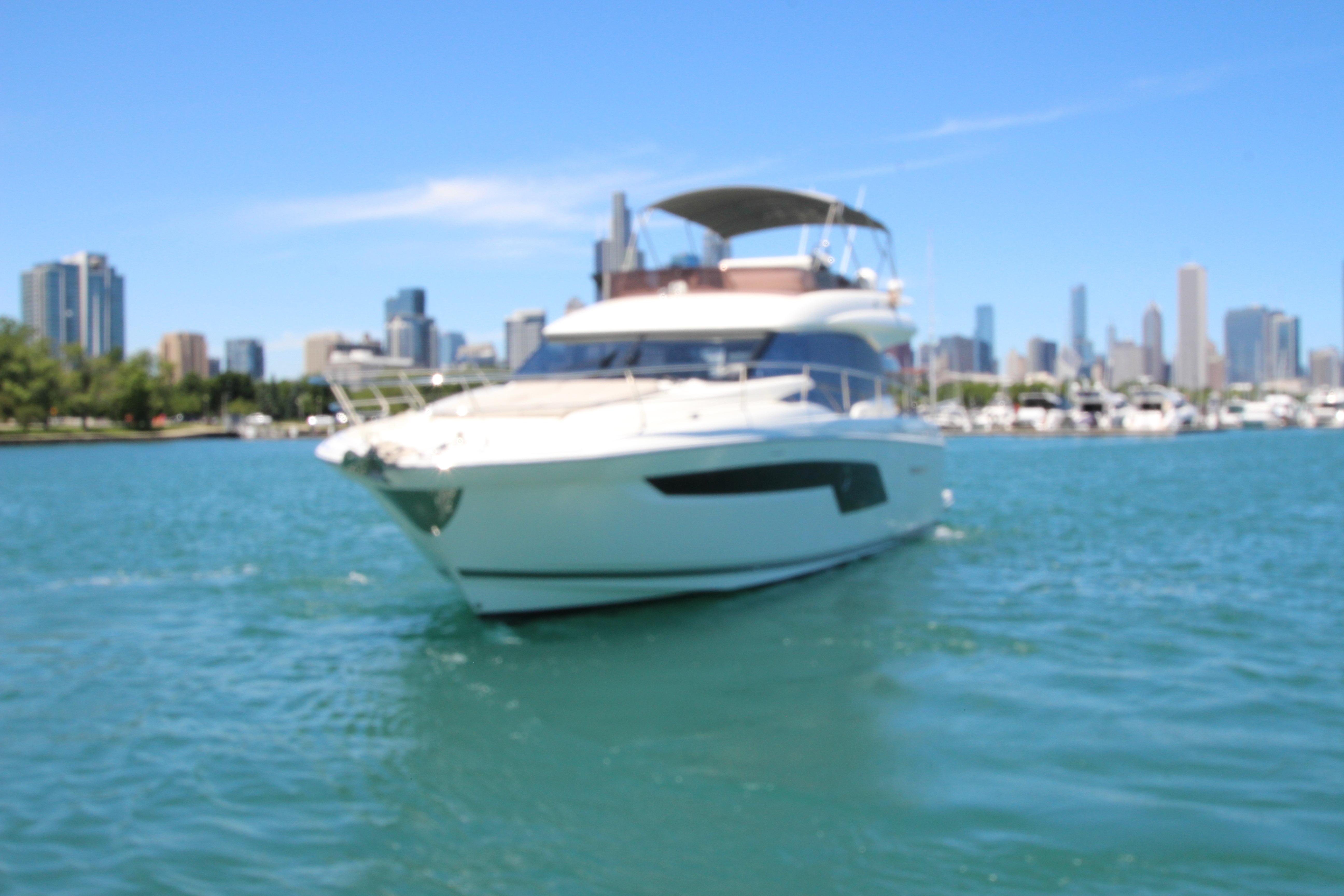 Luxury 2022 Prestige 520 yacht cruising near city skyline on a sunny day.