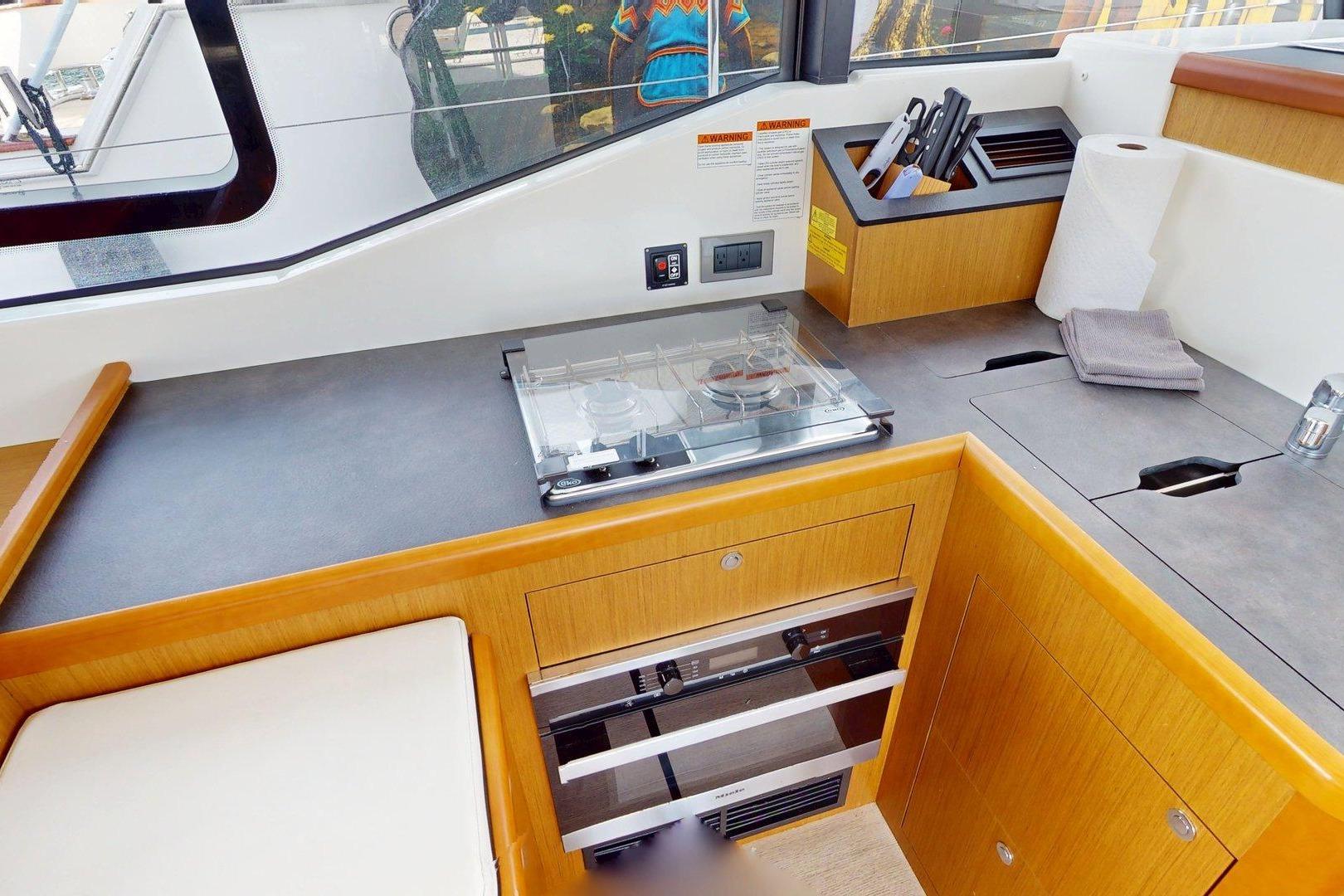 Modern kitchen area in 2021 Beneteau Swift Trawler 35 with stove and storage.