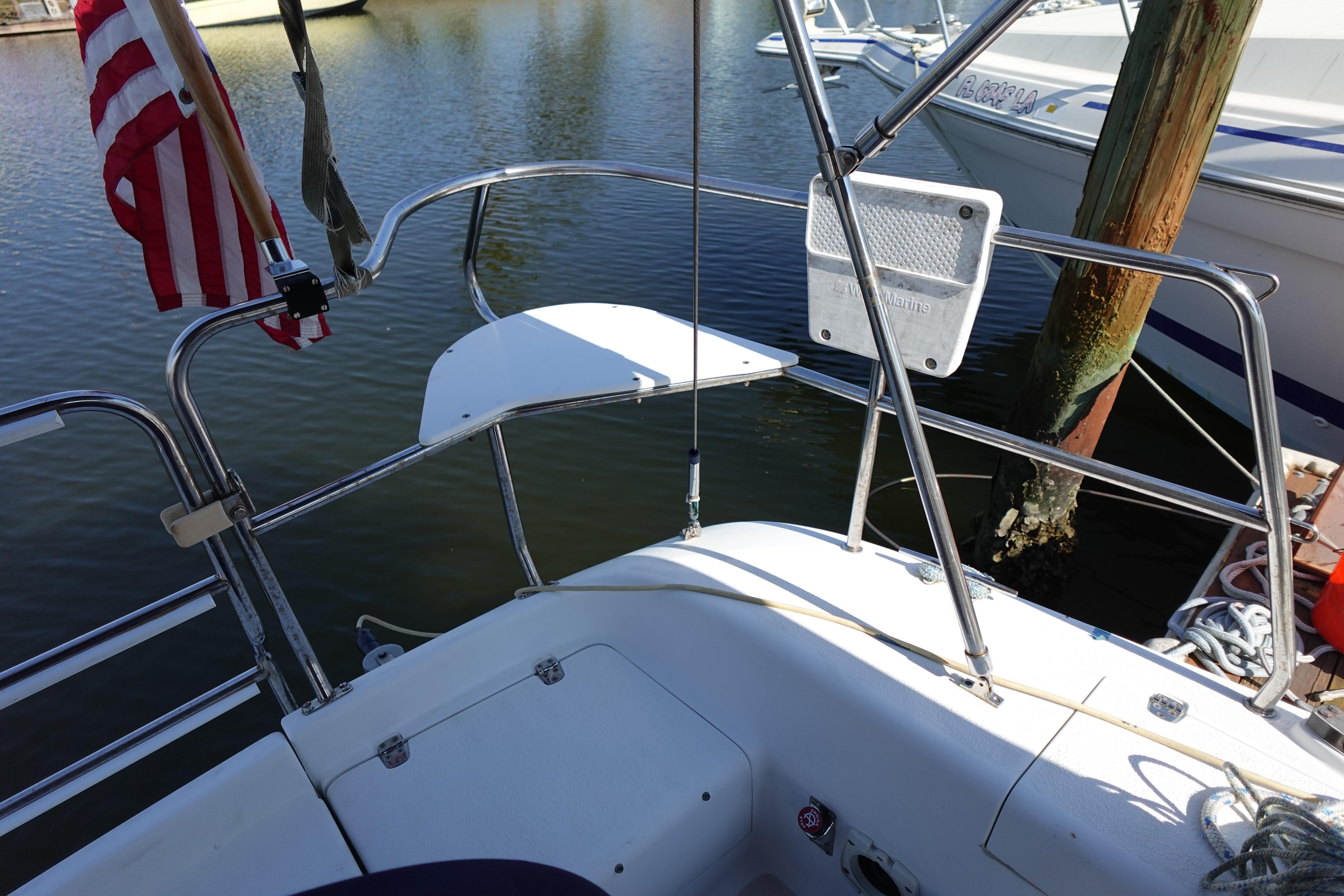 Cockpit view of a 1997 Catalina 28 sailboat docked, featuring stainless steel railings and an American flag.