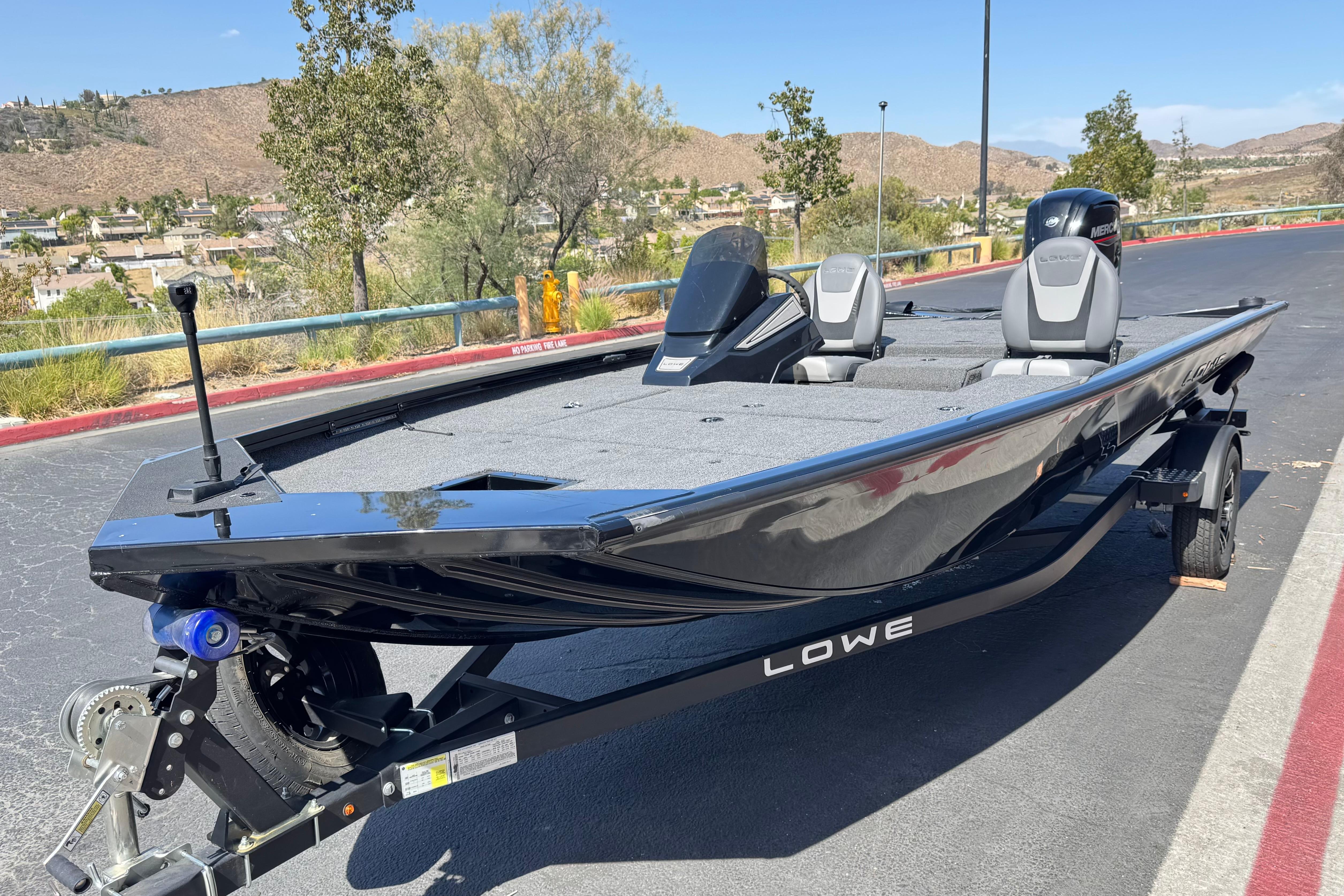 2024 Lowe Stinger 175 boat on trailer, parked outdoors with scenic background.