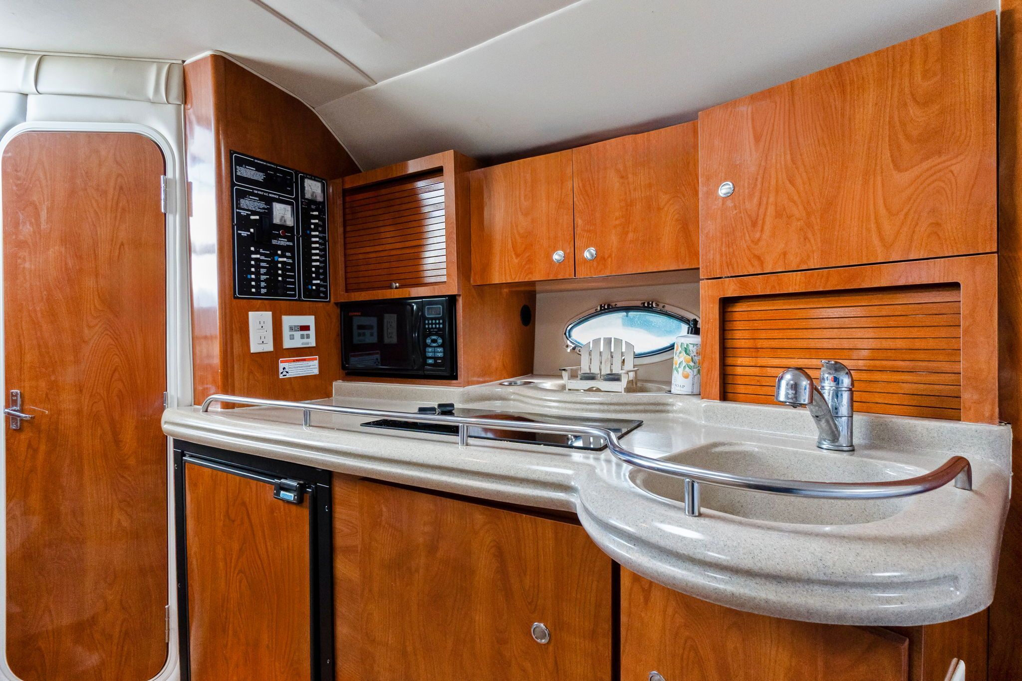 Interior of the 2007 Larson Cabrio 330 with wooden cabinets and a small kitchenette.