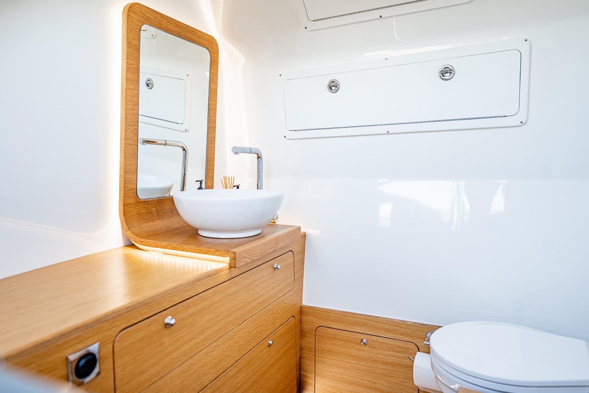 Modern yacht bathroom with wooden cabinetry, vessel sink, and mirror on Skipper-BSK 38NC, 2023 model.