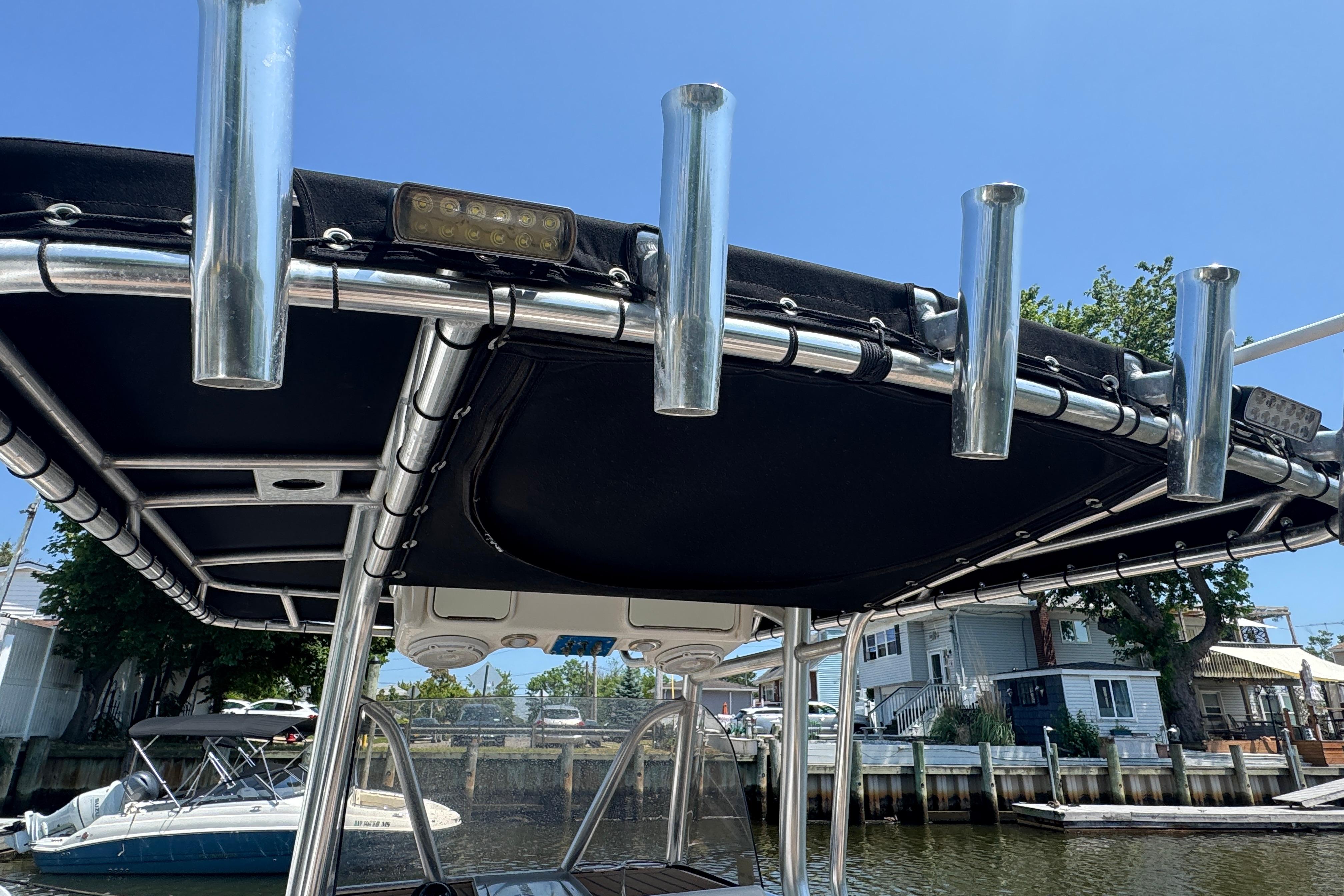 2014 Century 2301 Center Console boat with rod holders and canopy, docked by waterfront homes.