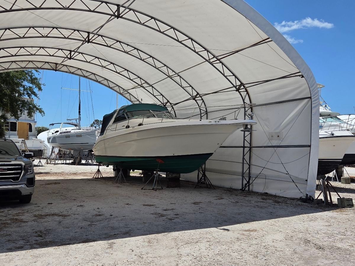 A 1995 Sea Ray Sundancer 330 is on stands under a covered area.