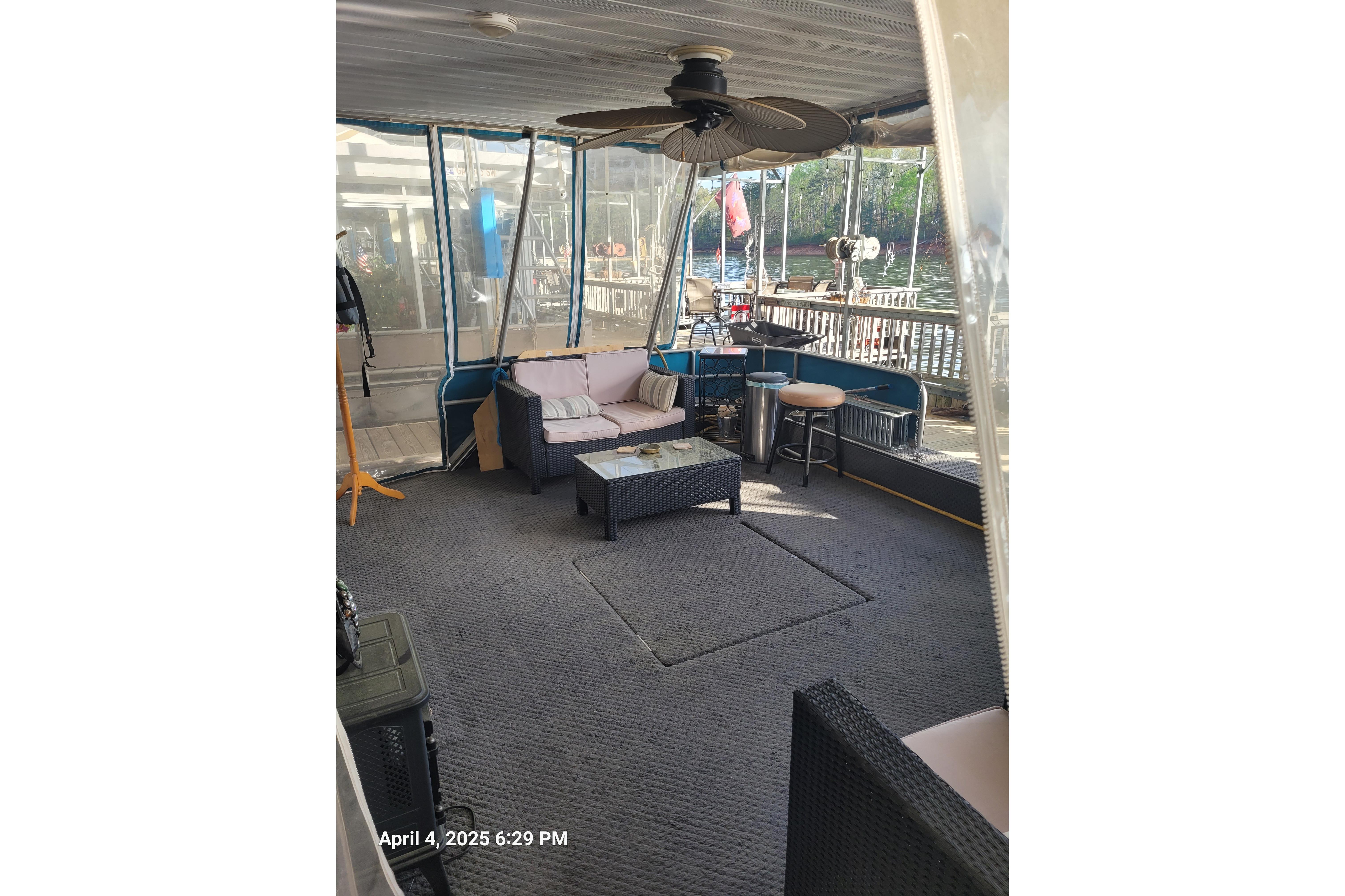 Enclosed deck area on a 1990 Sumerset 16 x 70 houseboat with seating and ceiling fan.