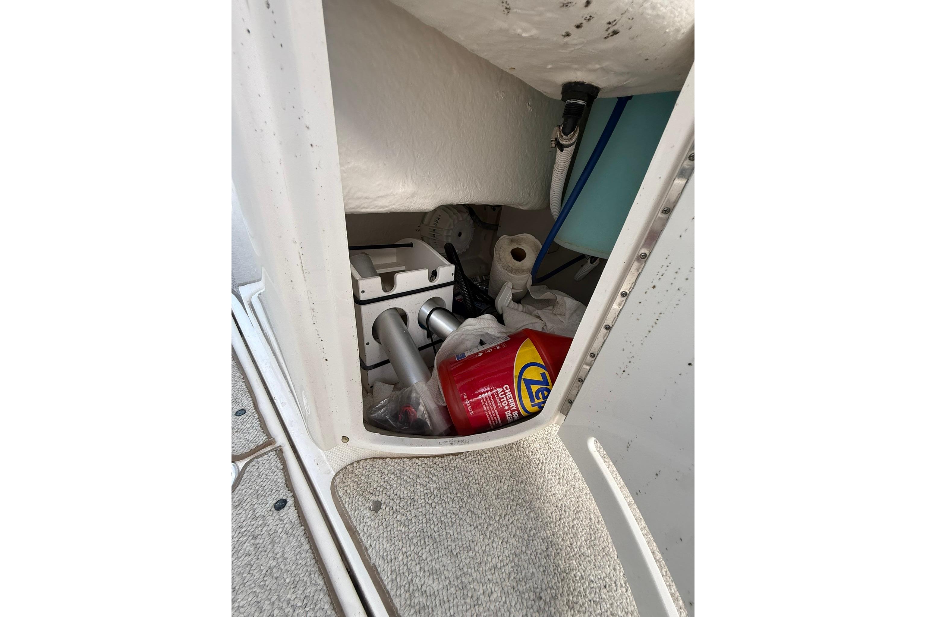 Storage compartment in a 2005 Sea Ray 290 SLX boat with cleaning supplies and equipment.