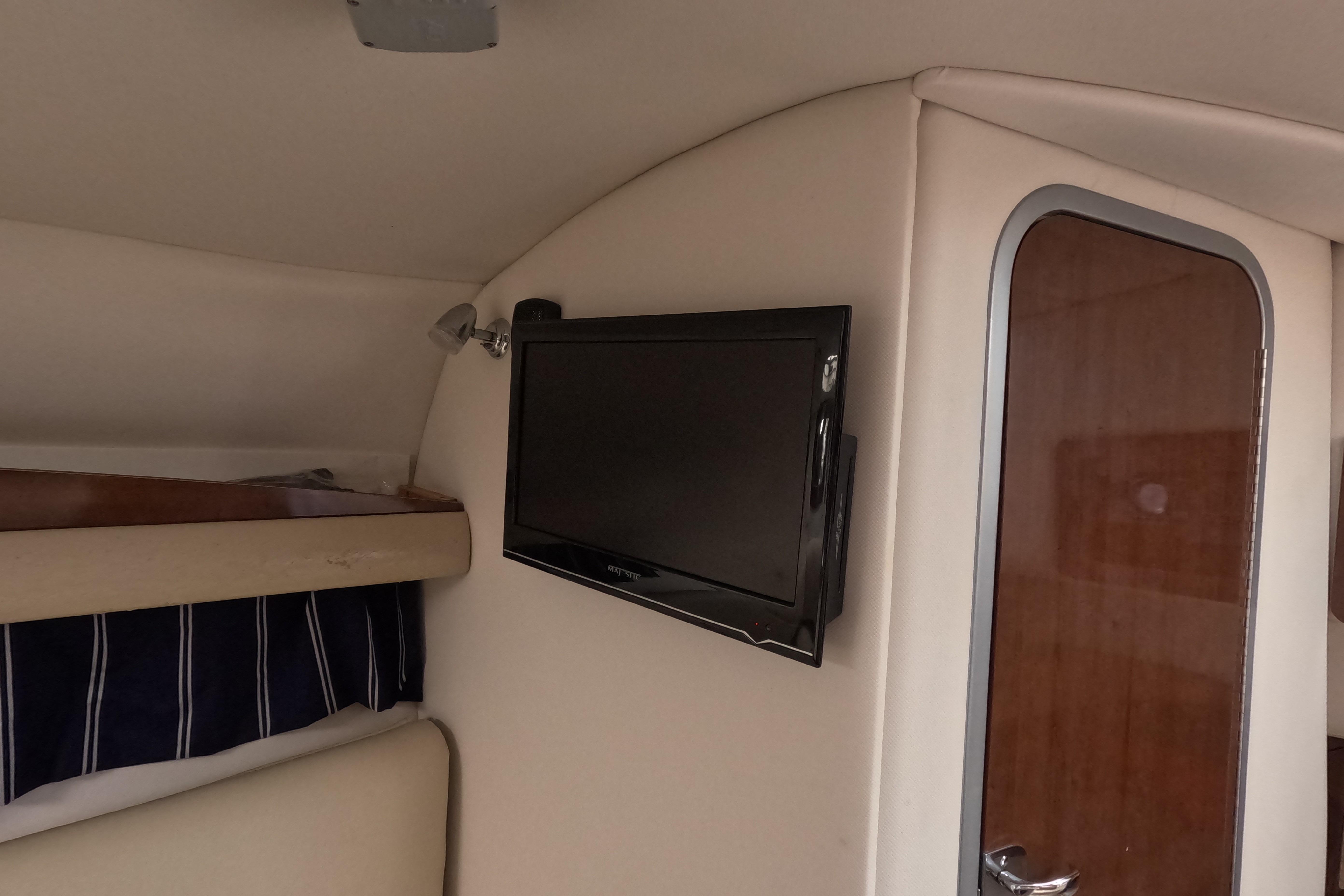 Interior of 2012 Four Winns V265 boat with mounted TV and wooden door.