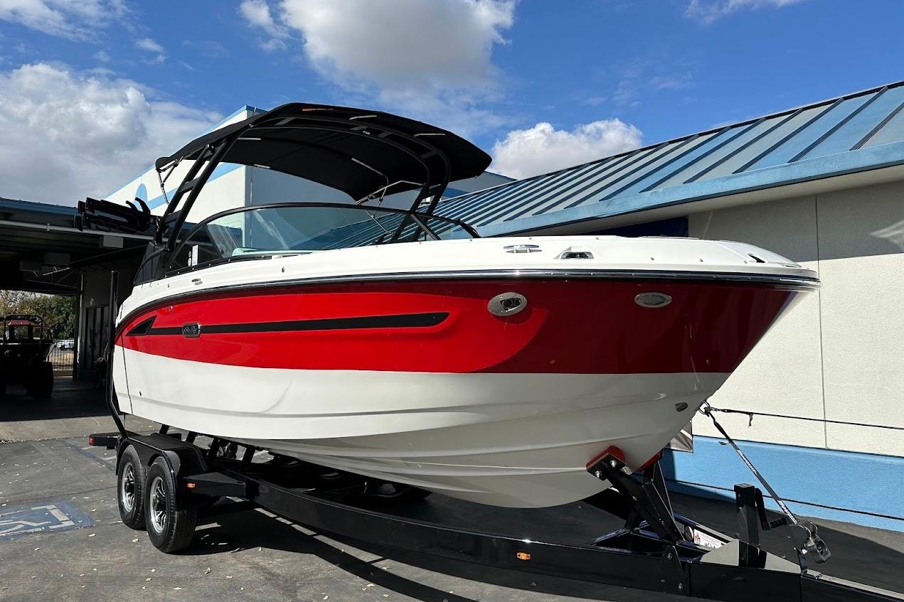 2026 Sea Ray SDX 230 Surf boat with red and white hull on trailer, outdoors.