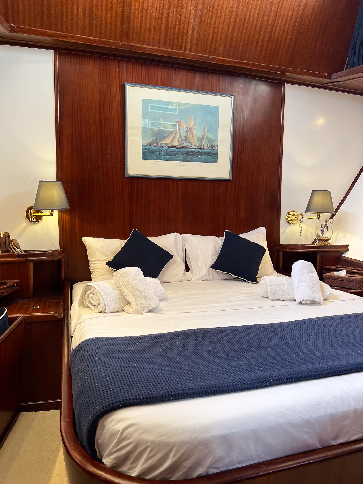 Luxurious cabin interior of a 1969 Psarros Shipyard yacht with elegant bedding and nautical decor.