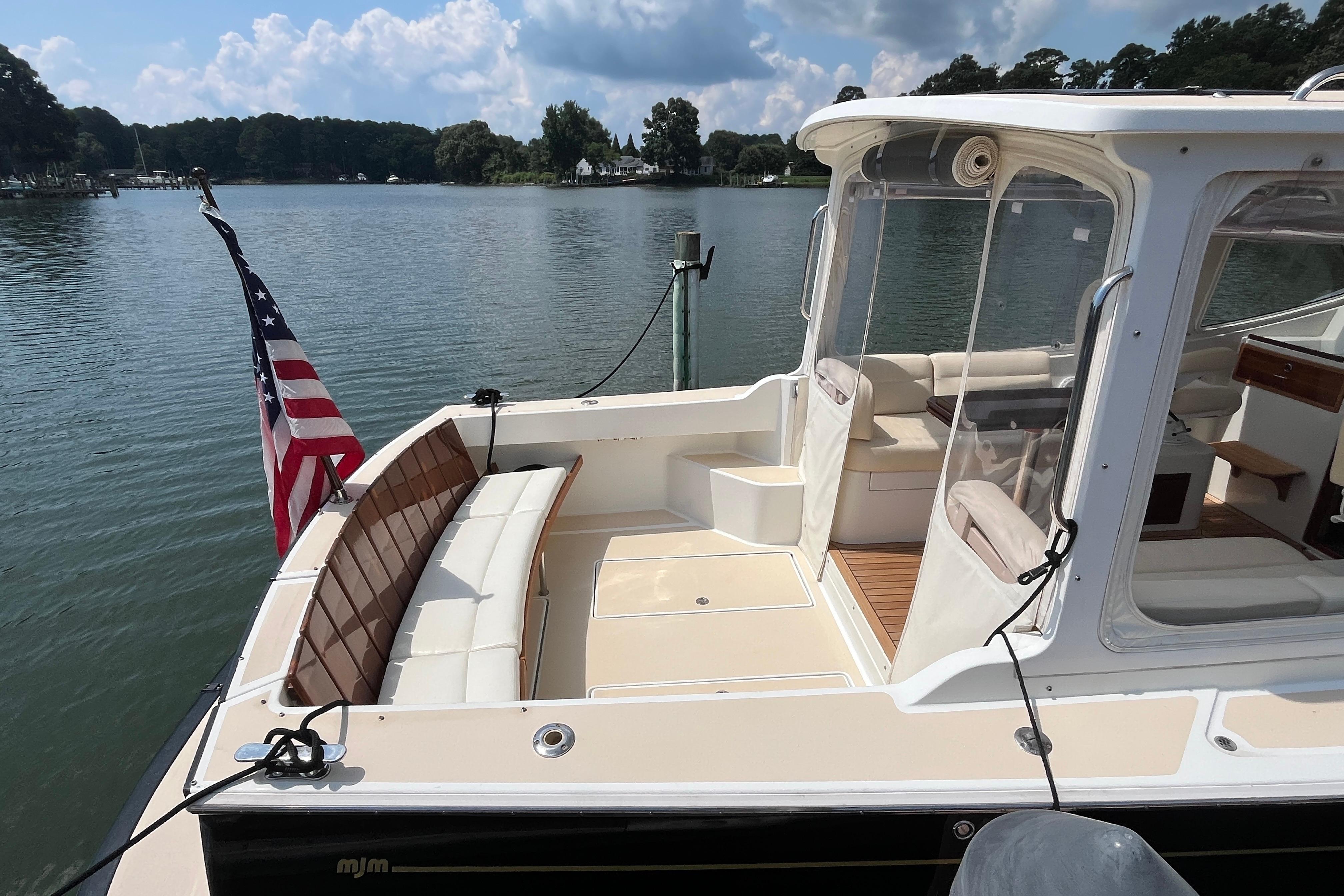 2006 MJM 34z boat with American flag, docked on a serene lake.