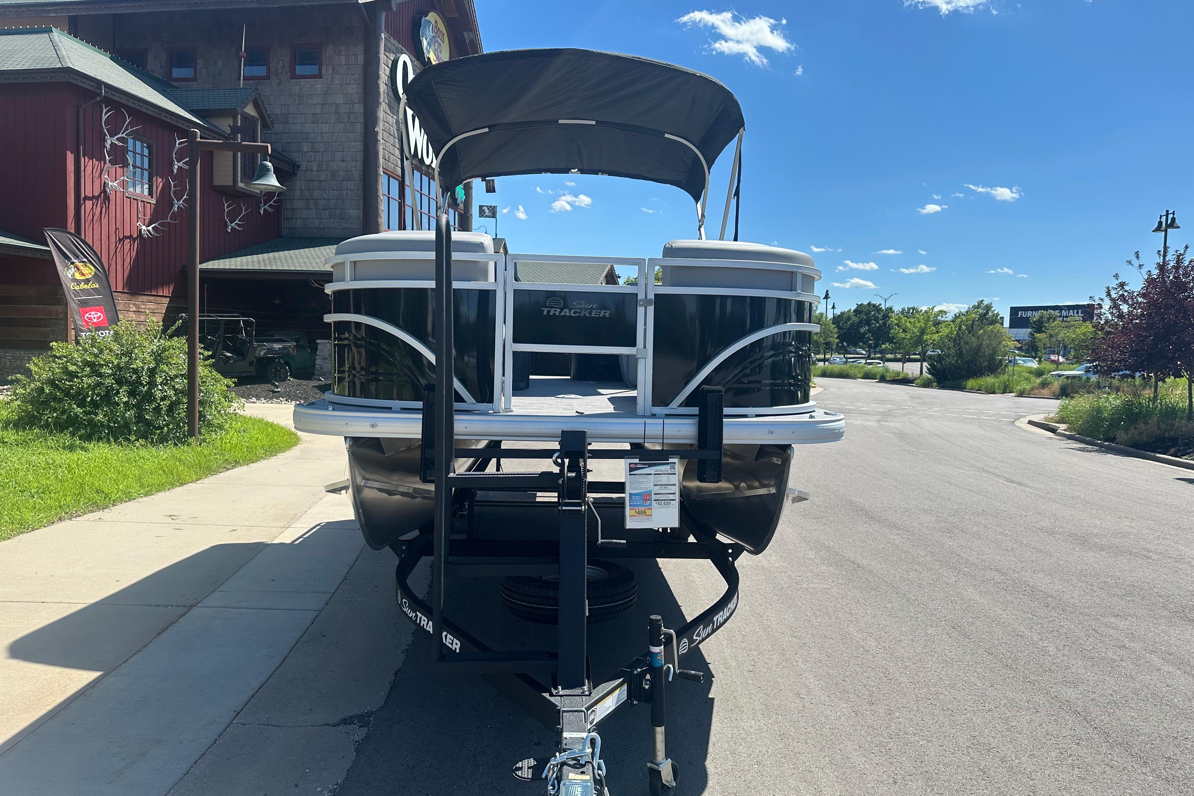 2026 Sun Tracker SportFish 22 DLX pontoon boat parked outside a rustic building.