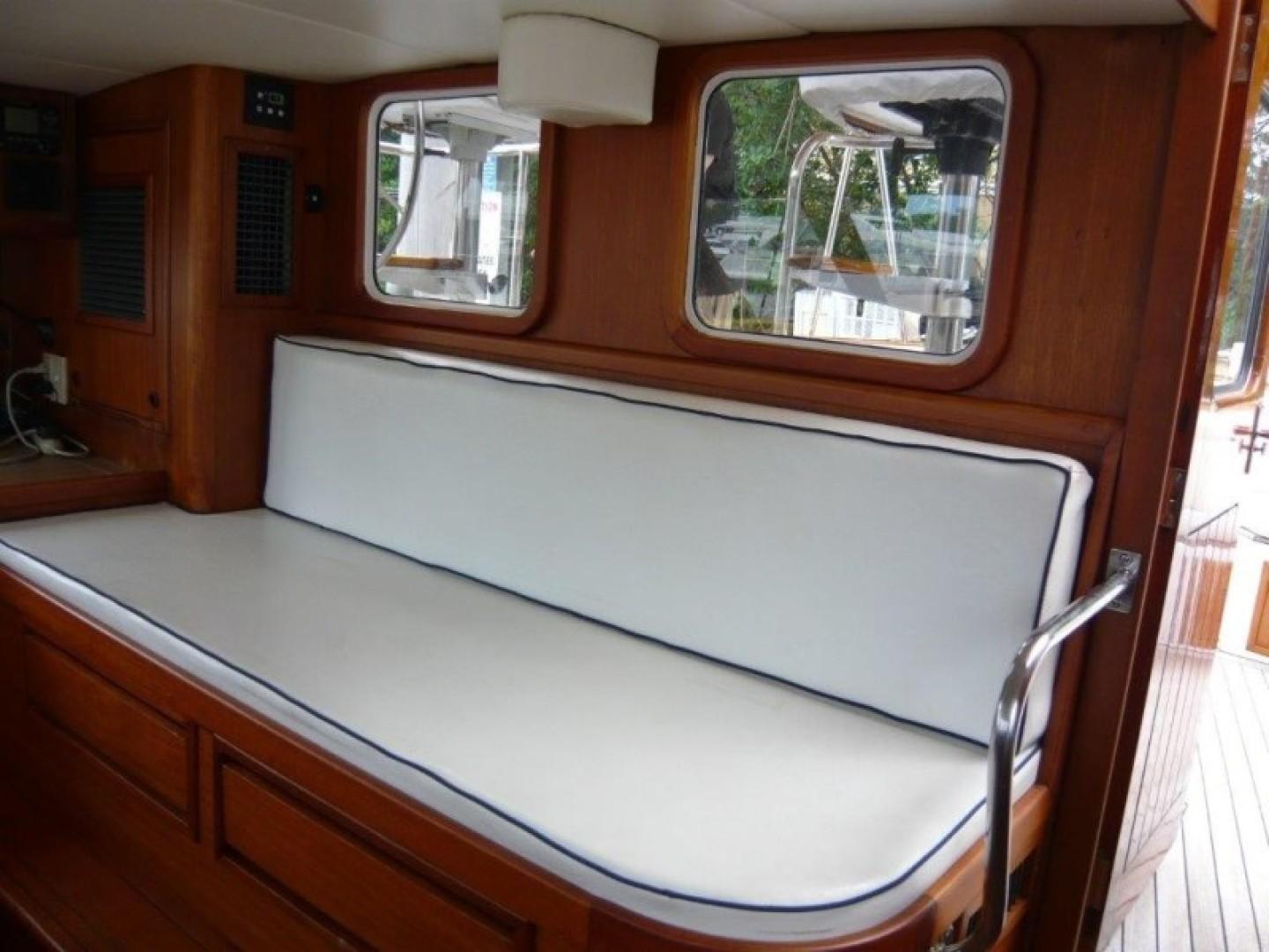 Interior of 1990 Cheoy Lee Sloop with white cushioned seating and wooden finish.