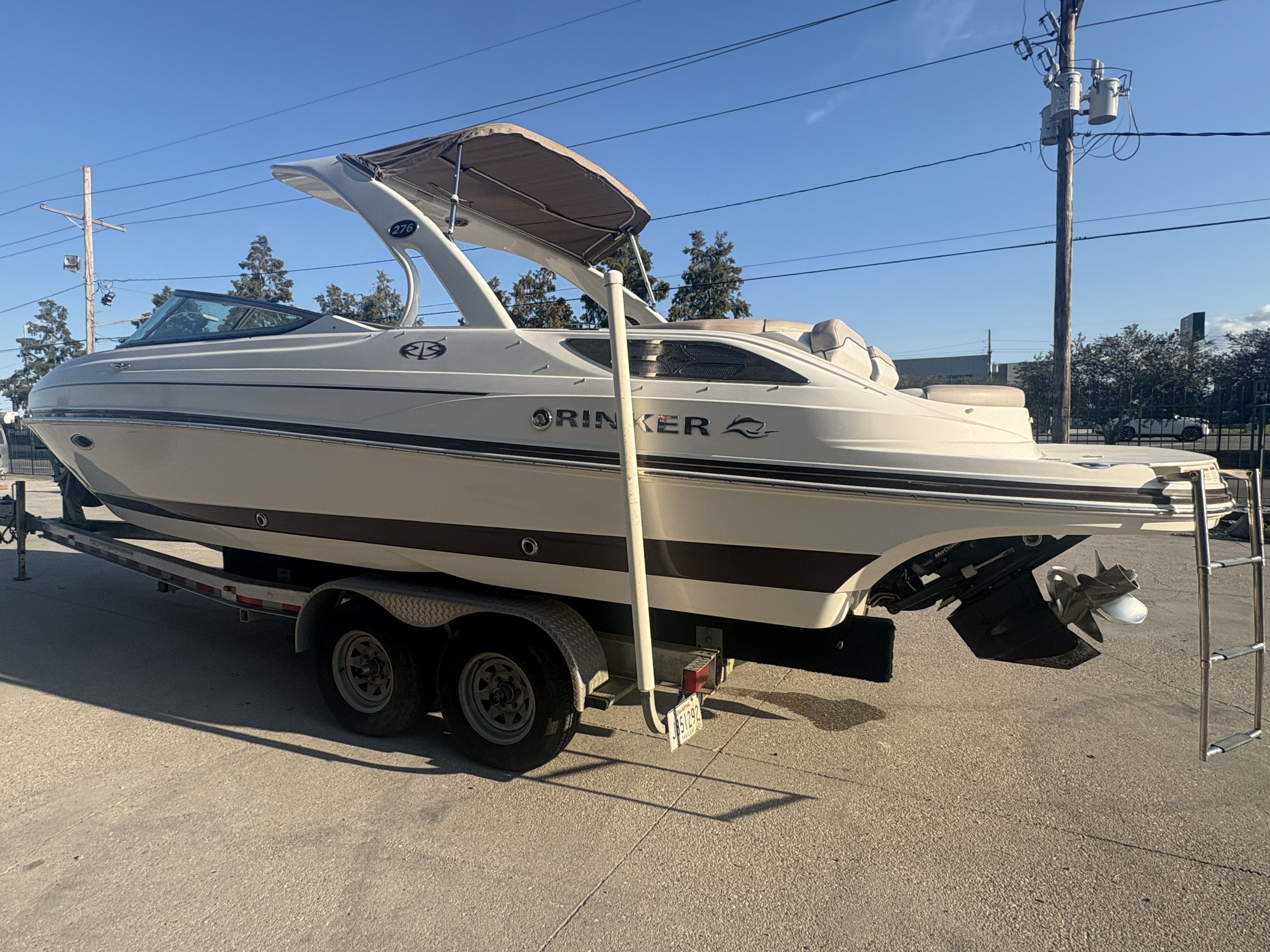 2013 Rinker Captiva 276 boat on trailer, parked outdoors under clear sky.