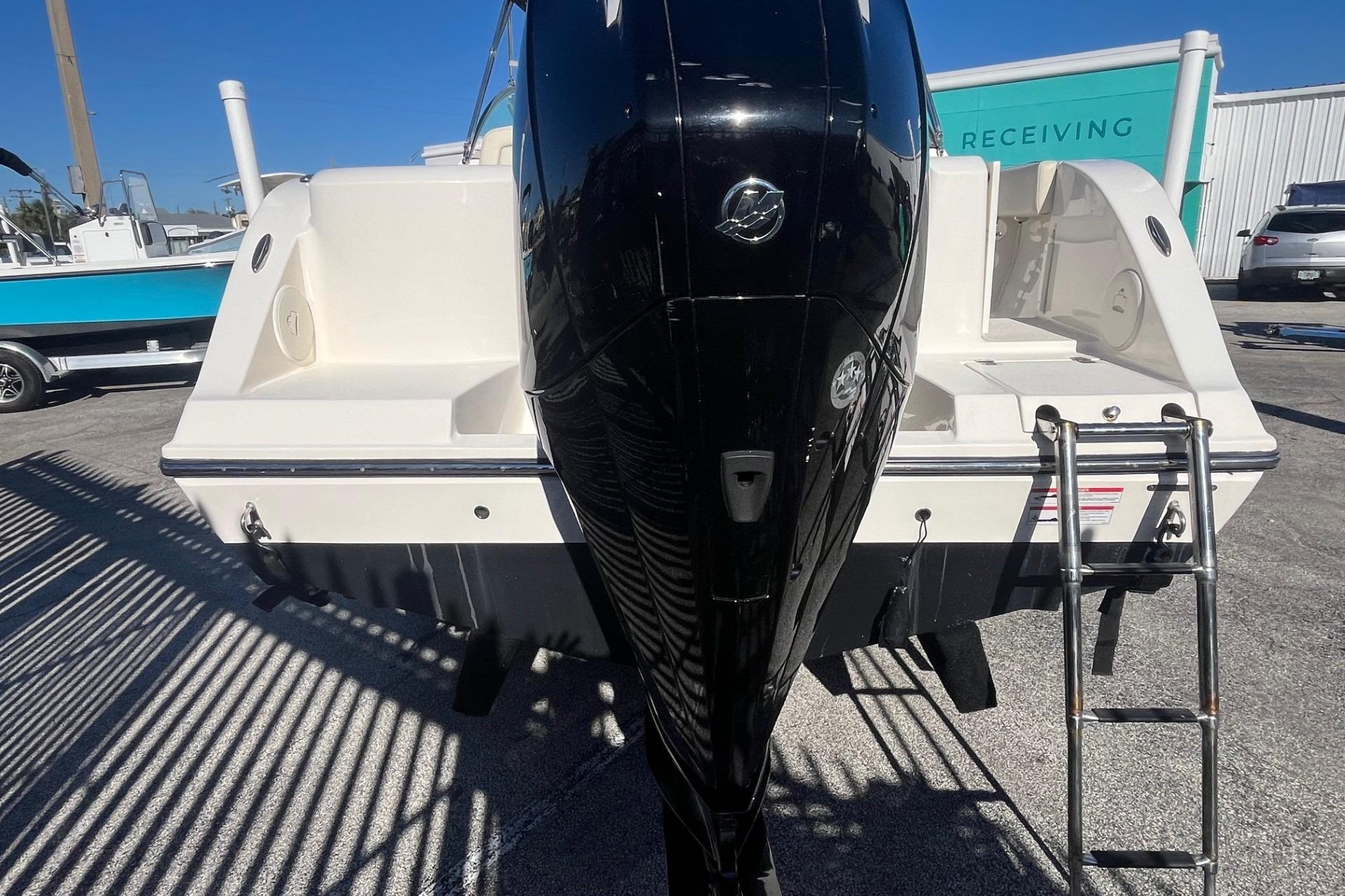 2023 Cobia 220 Dual Console boat with outboard motor and ladder, parked outdoors.