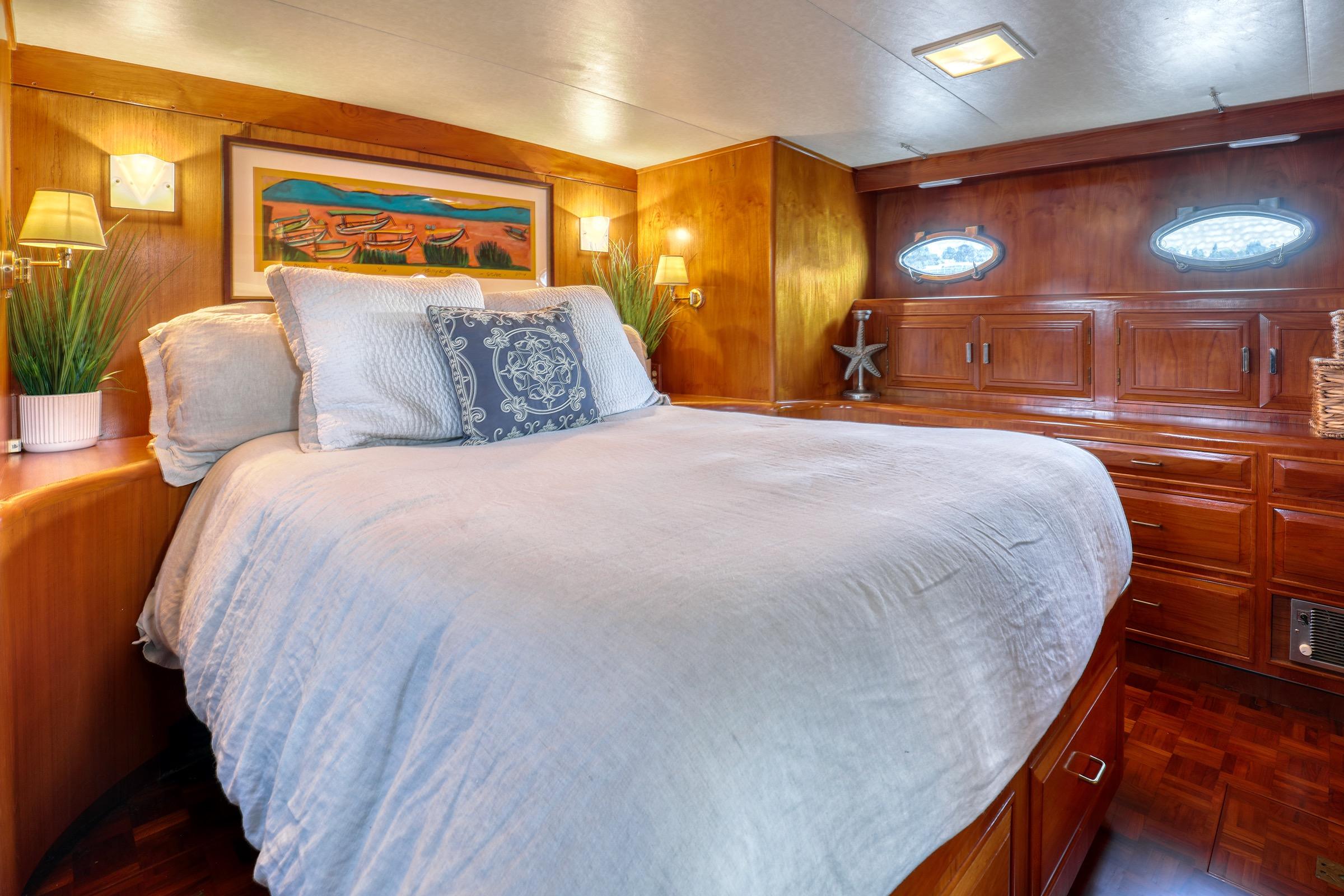 Luxurious 1987 Ocean Alexander 480 Sport Sedan bedroom with elegant wood paneling and cozy bedding.