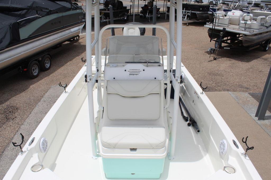 2026 Skeeter SX230 boat interior with white seating, rod holders, and console, docked among other boats.