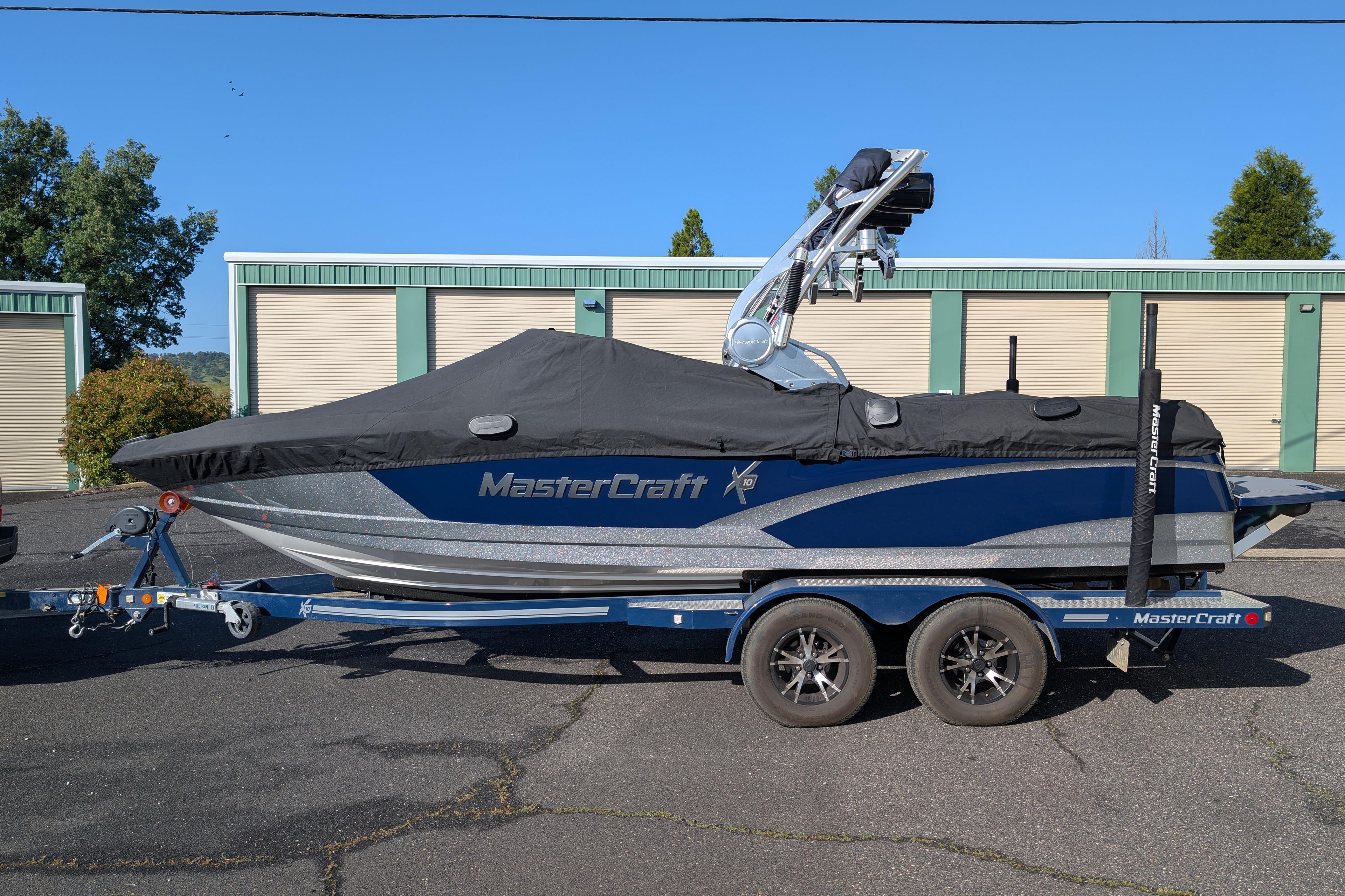 2016 MasterCraft X10 boat on trailer, covered, parked outdoors.