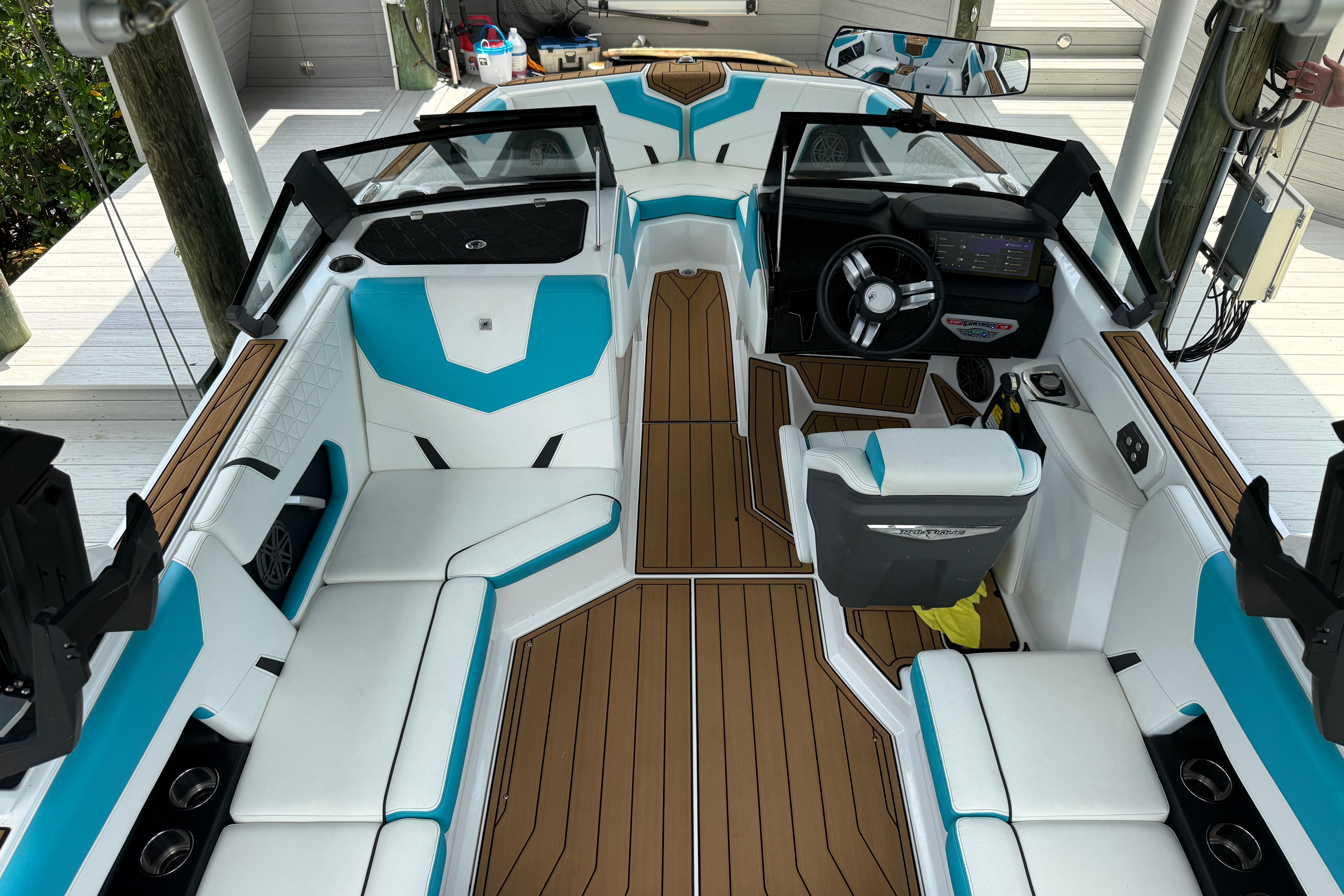 2024 Nautique Super Air Nautique GS20 boat interior with white and blue seating, brown flooring.