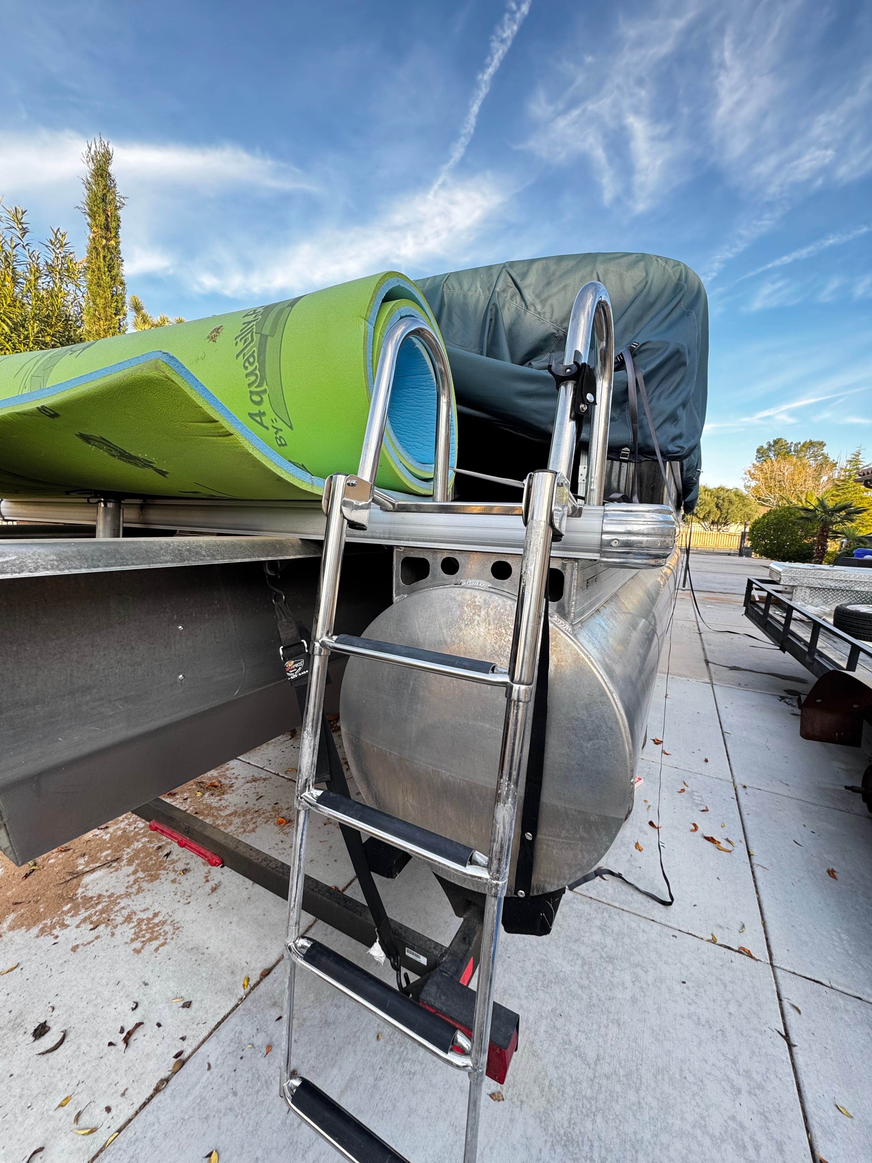 2023 Sun Tracker Sportfish 24 XP3 with ladder and green mat.