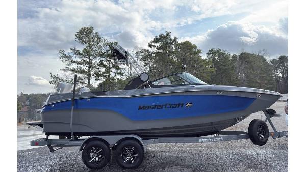 2023 MasterCraft XT22 boat on trailer, blue and gray design, parked outdoors.