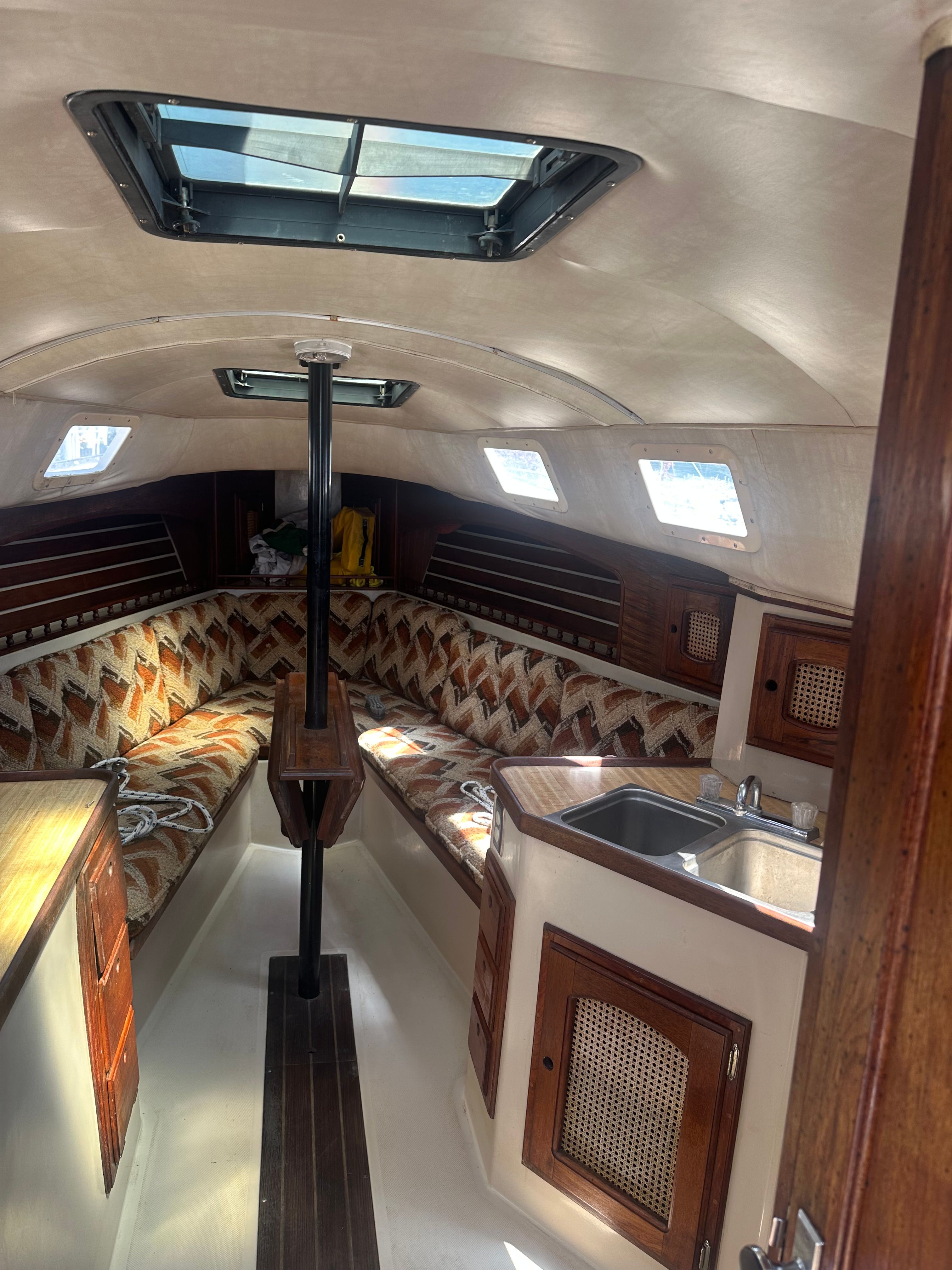 Interior of a 1982 Lancer 30 yacht with cozy seating and a small kitchenette.