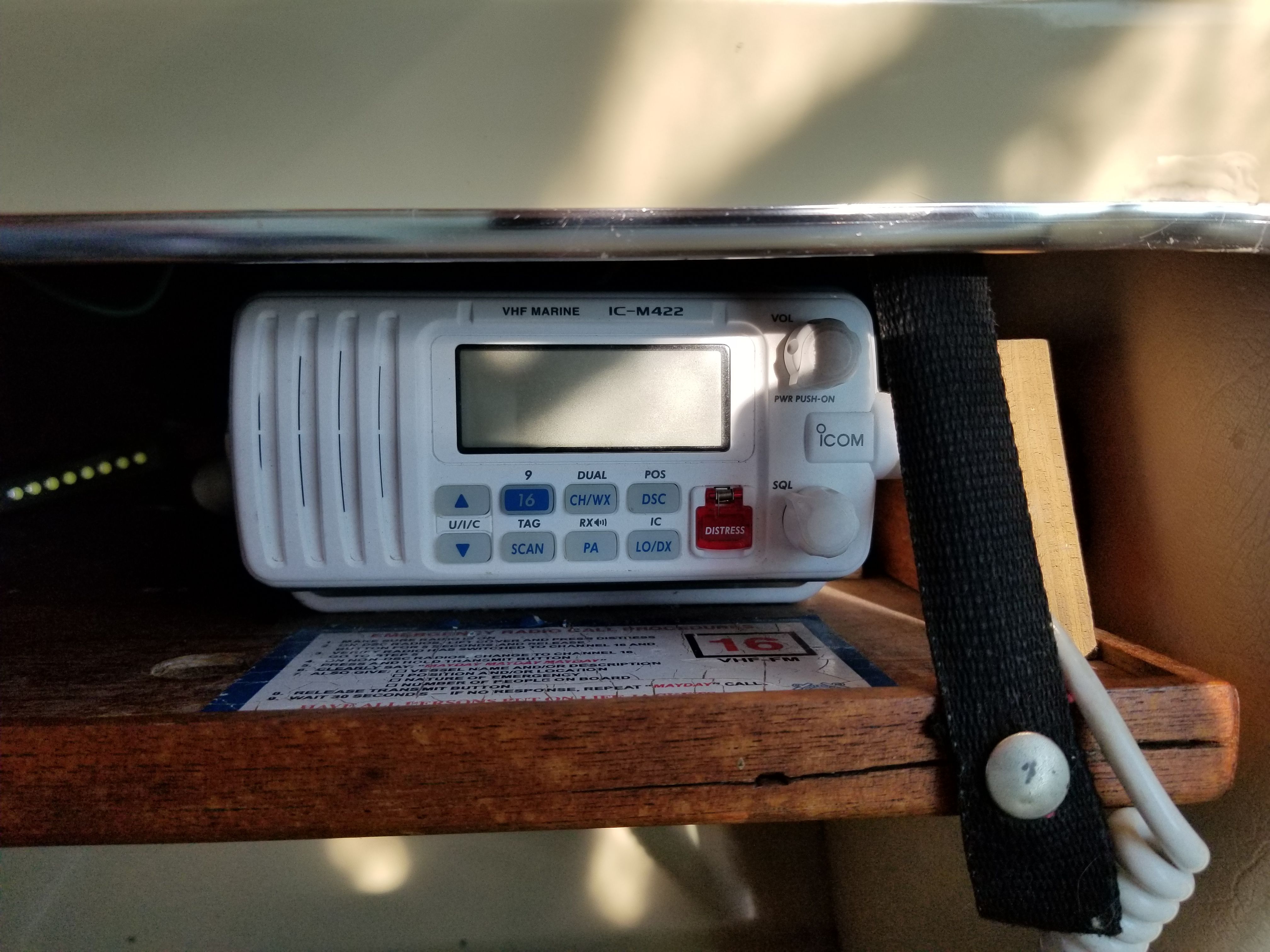 A VHF marine radio is mounted on a shelf inside a boat.