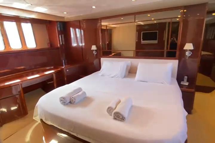 Luxurious bedroom interior of 2007 Princess 21M yacht with elegant wood finish and cozy bedding.