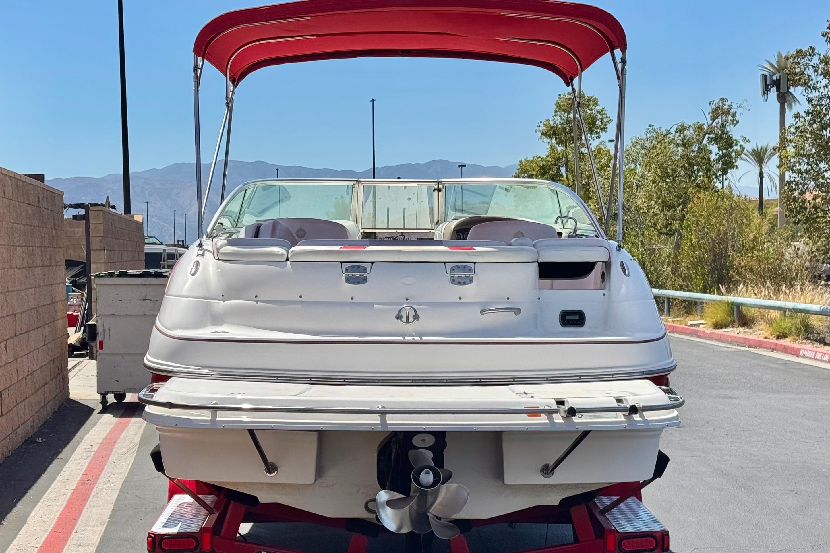 2010 Bryant 255 boat with red canopy, parked outdoors on a sunny day.