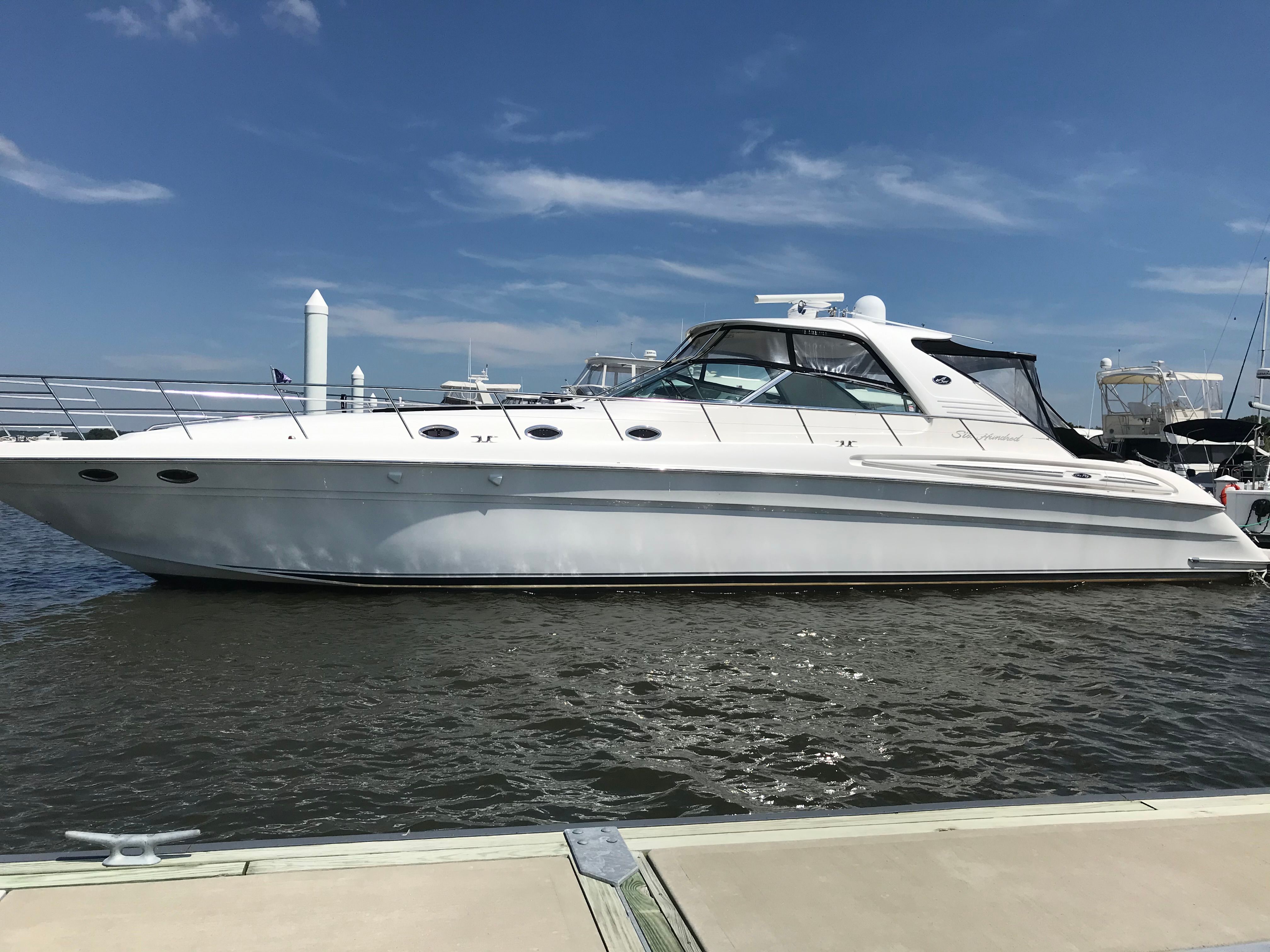 A white 2003 Sea Ray S600 Sunsport boat is docked on the water.