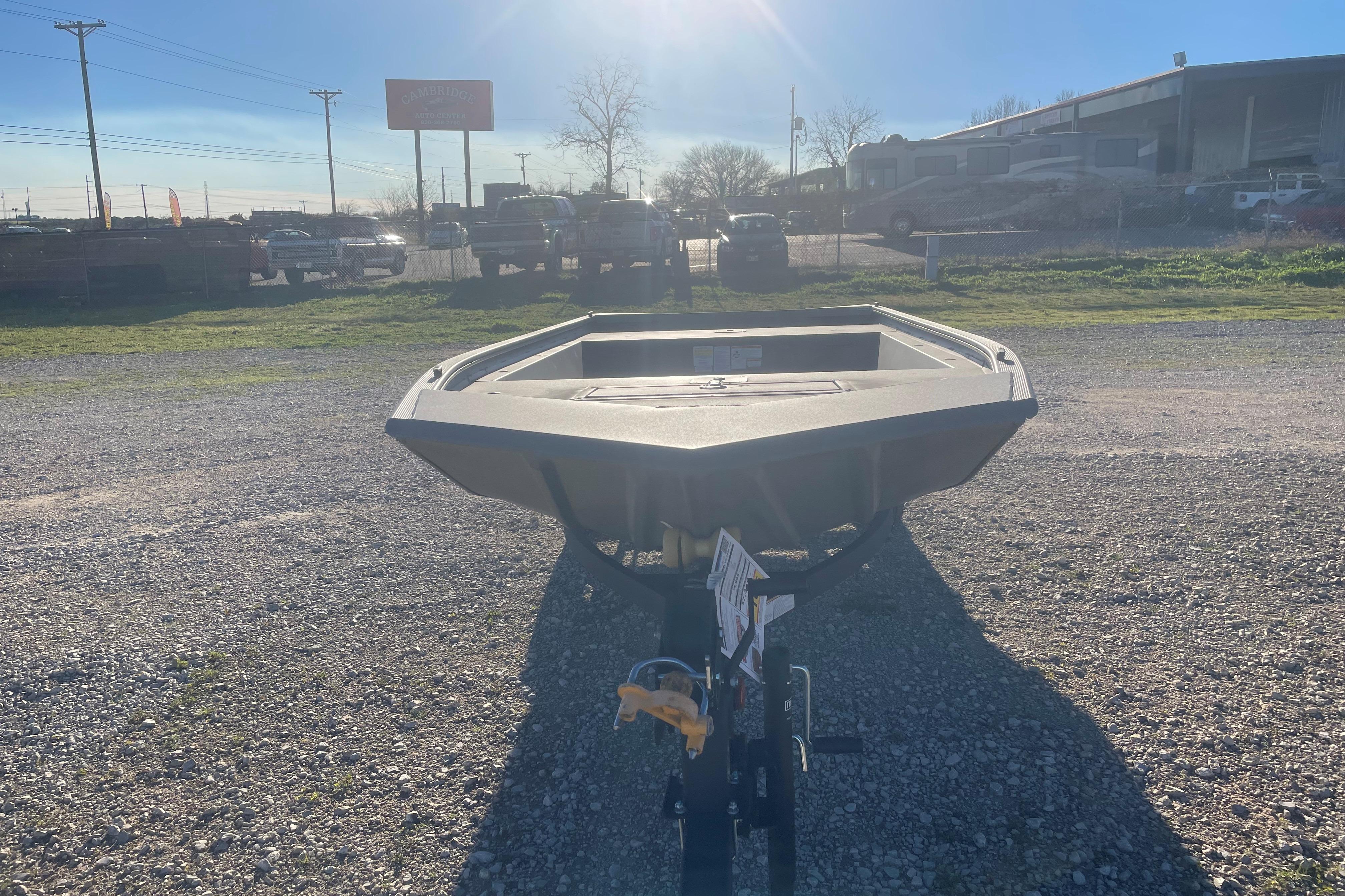 2026 Tracker Grizzly 1648 Utility boat on gravel lot under sunny sky.