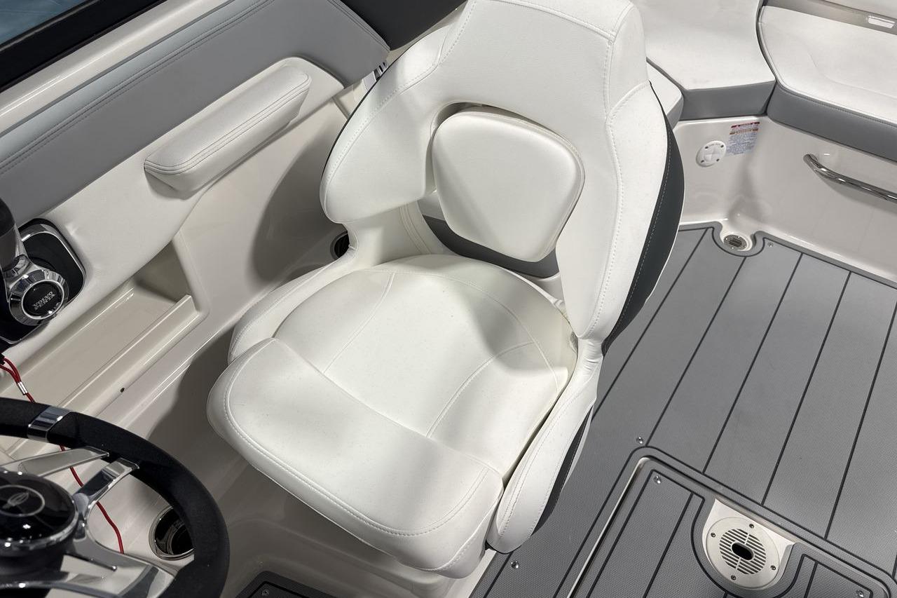 A sleek white captain's chair on a modern boat with gray flooring.