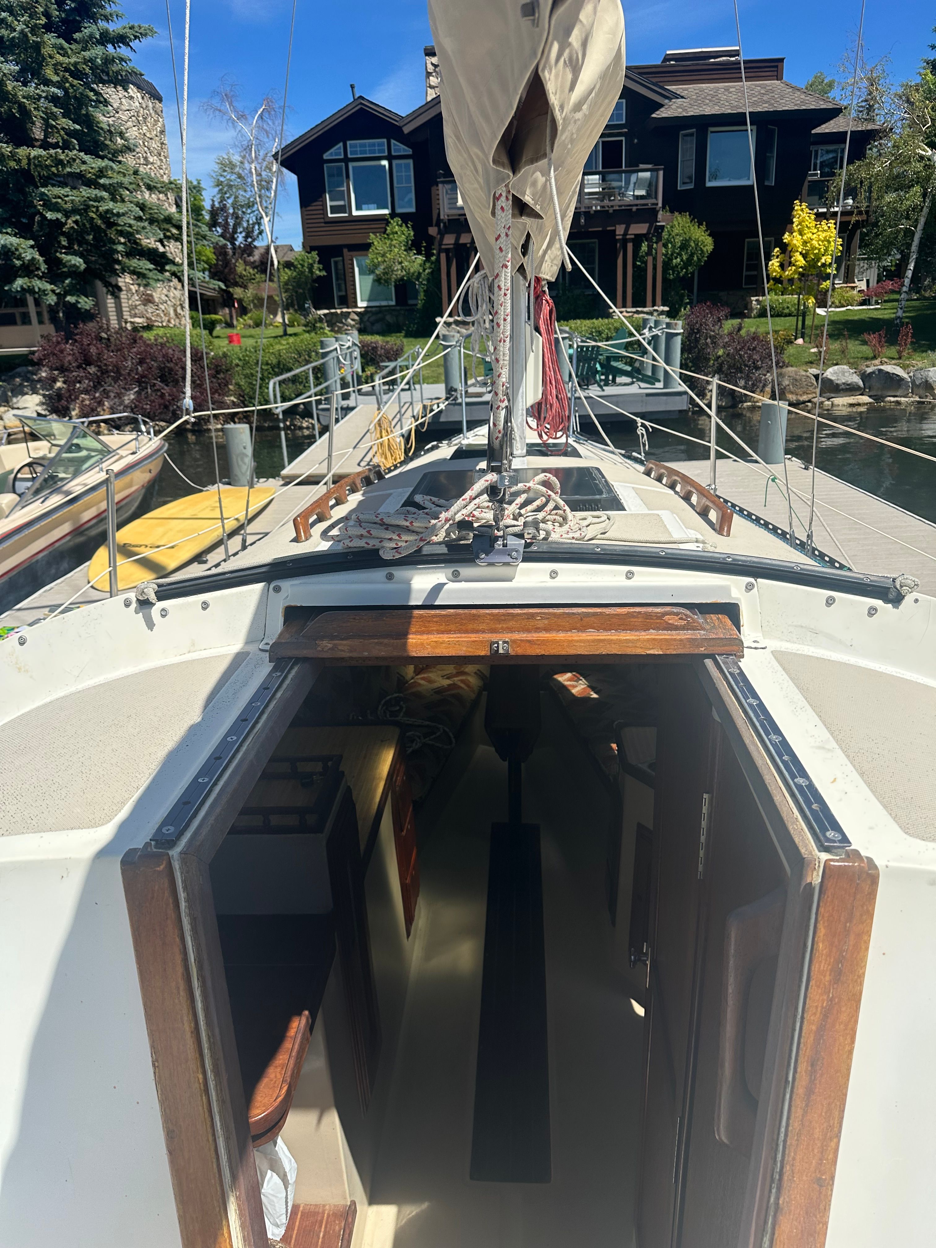 A 1982 Lancer 30 sailboat docked. The cabin entrance is open, showing the interior.
