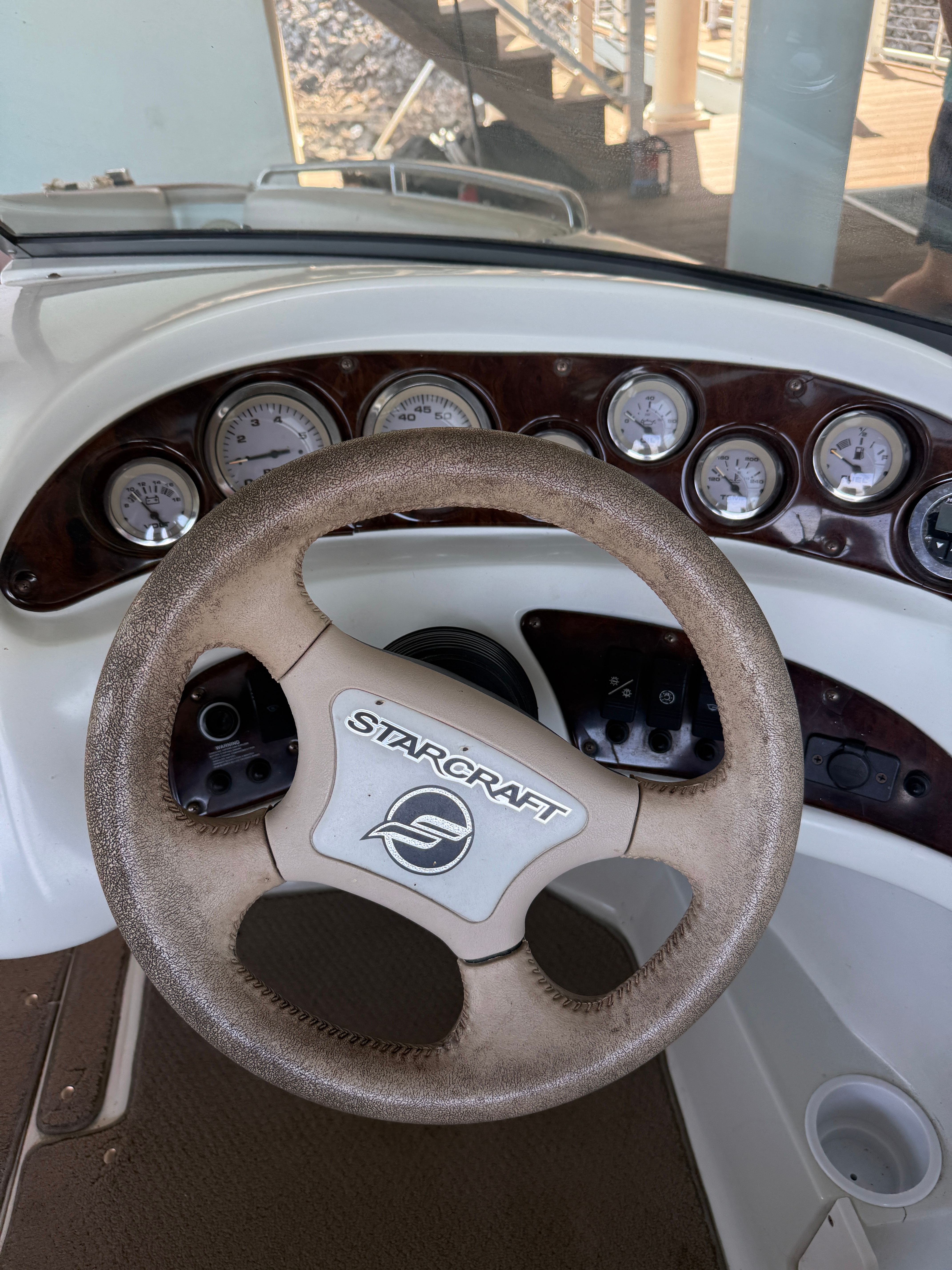 Helm of a 2000 Starcraft Next Star 19 boat with a worn steering wheel and gauges.