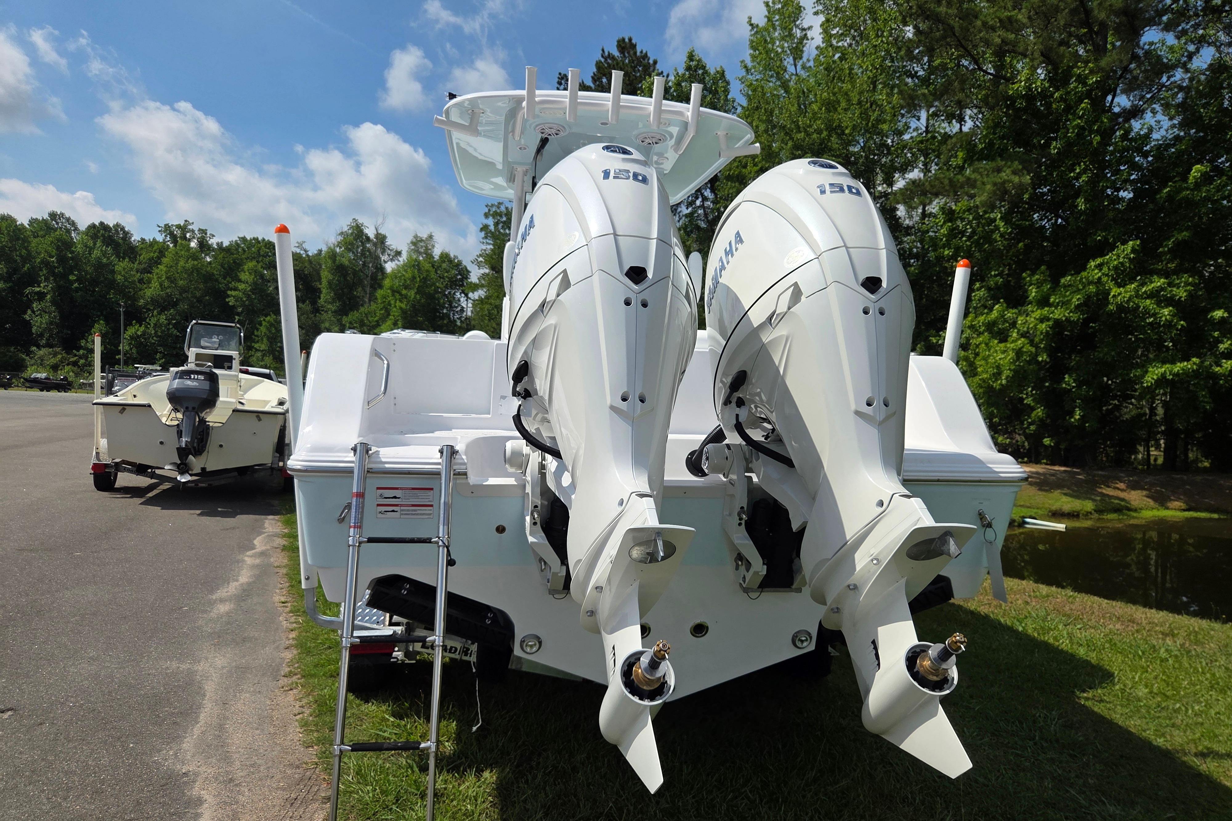 2026 Sportsman Open 252 Center Console with dual outboard engines, parked on grass.