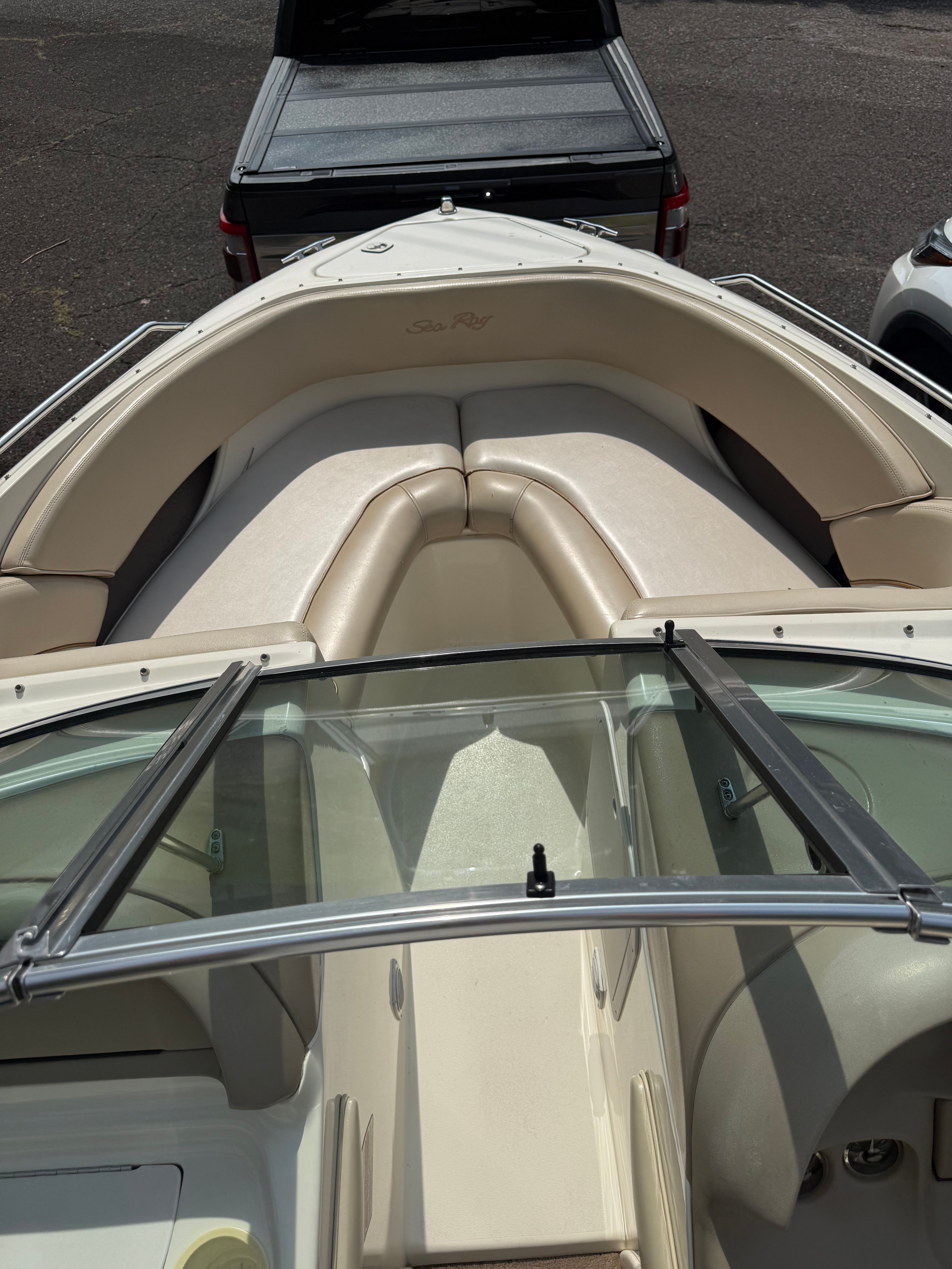 A 1999 Sea Ray 210 Bow Rider Signature with beige upholstery and a glass windshield.