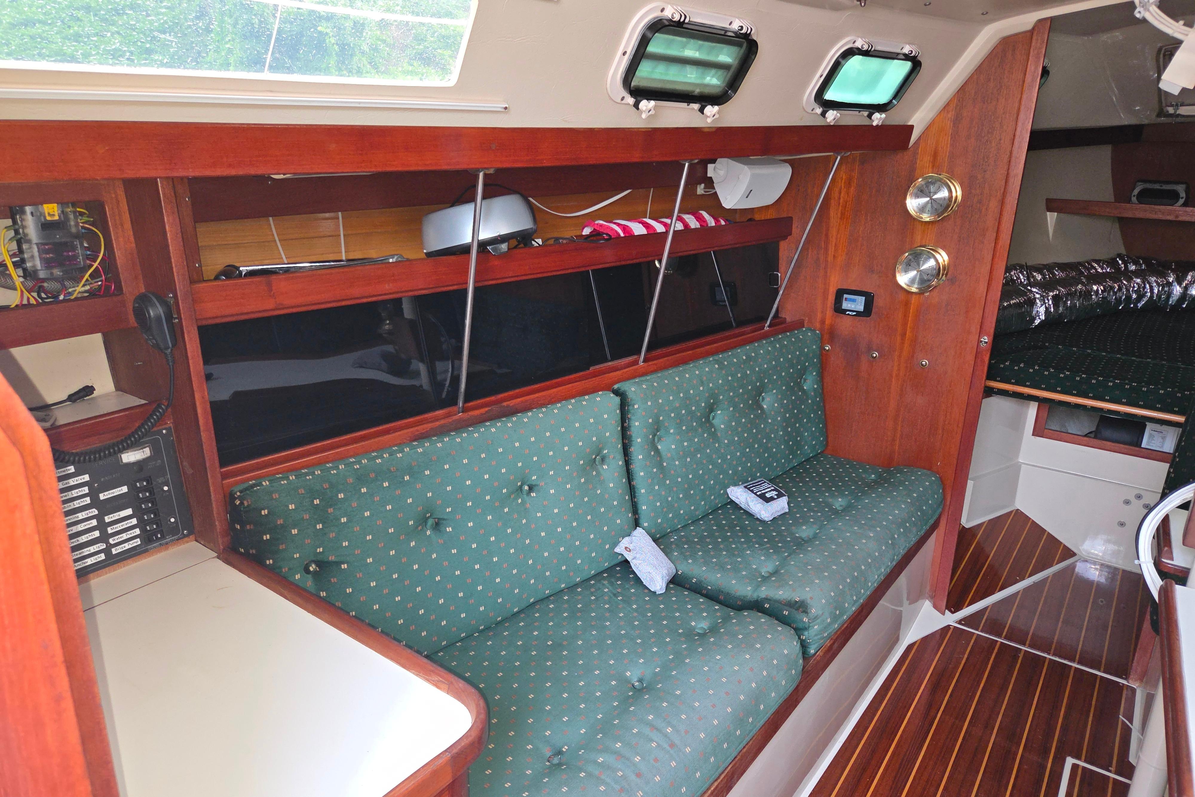 Interior of 1986 Catalina 355 sailboat with green cushioned seating and wooden accents.