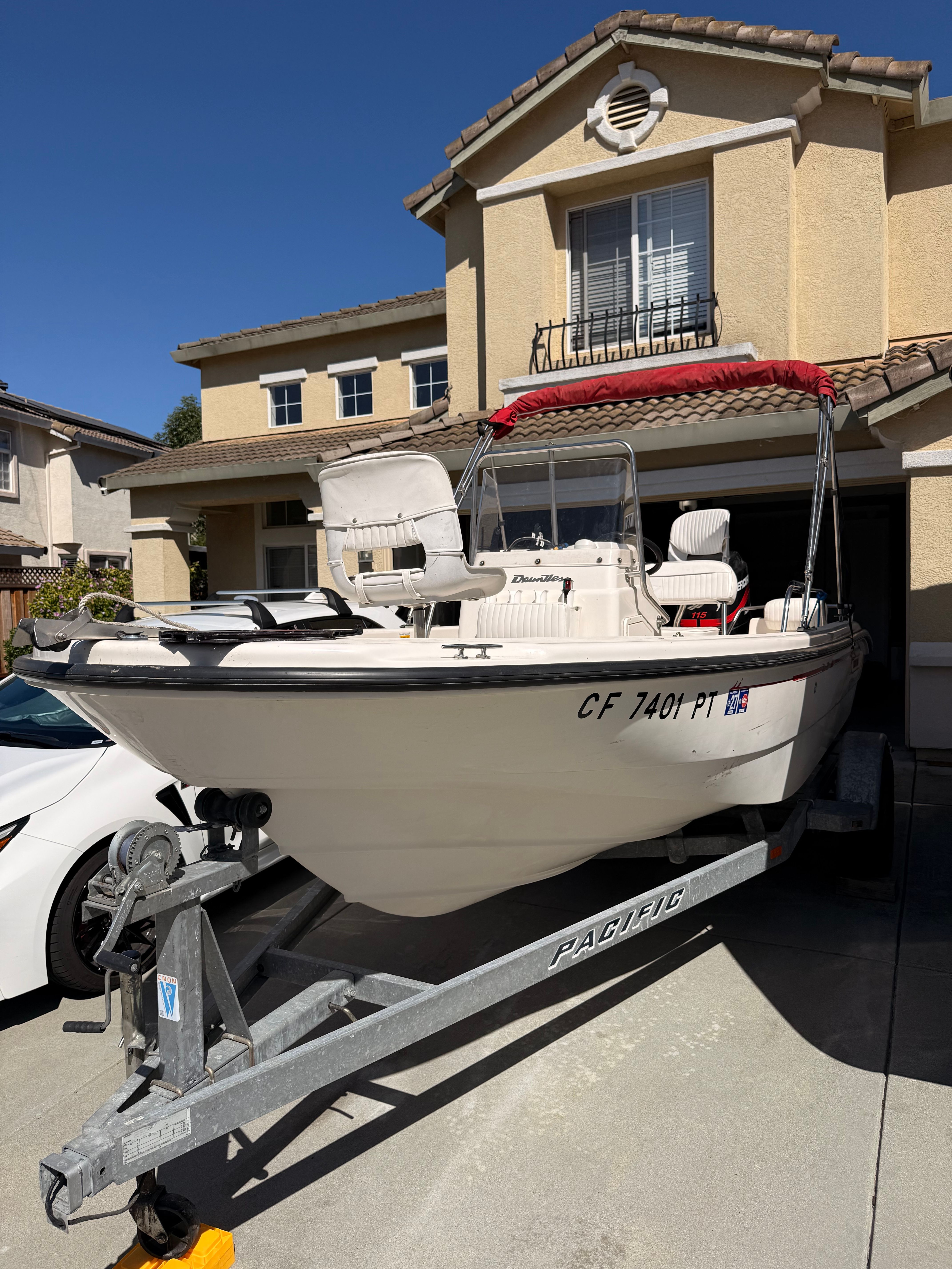 A 2002 Boston Whaler 160 Dauntless on a trailer in front of a house.