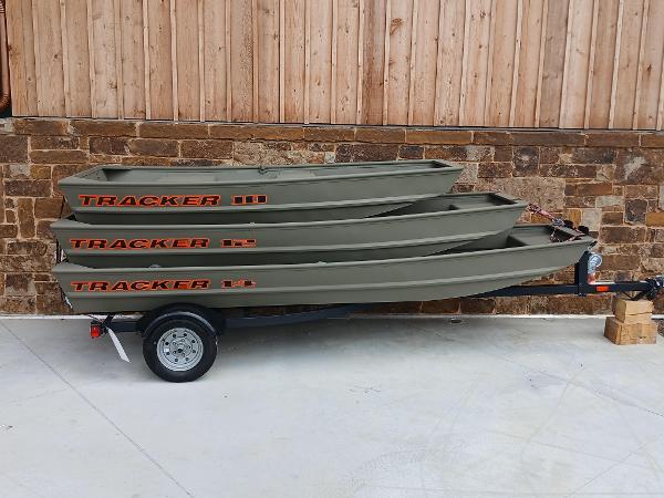 2025 Tracker Grizzly 1036 Utility boats stacked on a trailer, against a wooden wall.