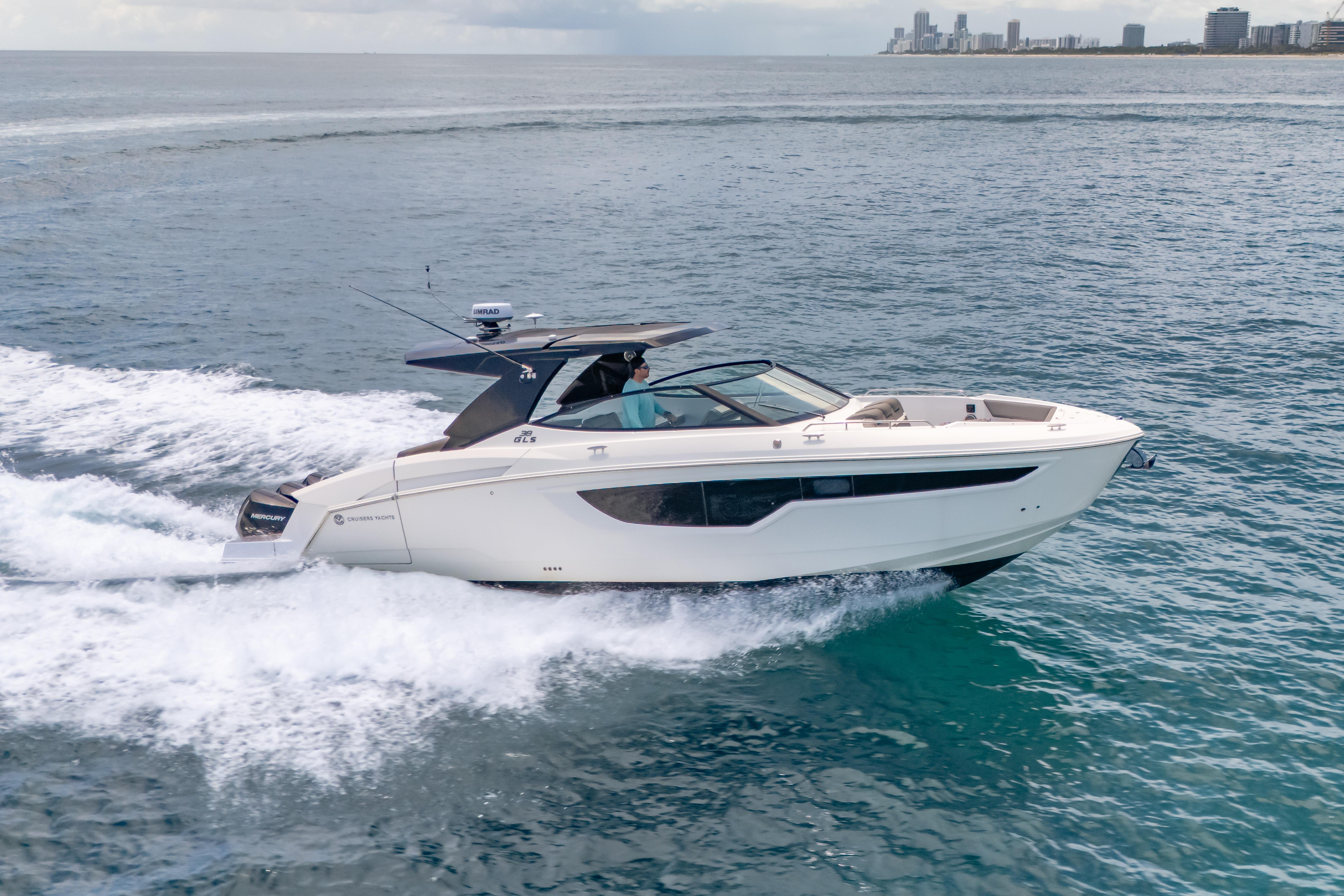 2021 Cruisers Yachts 38 GLS speeding on open water, city skyline in background.