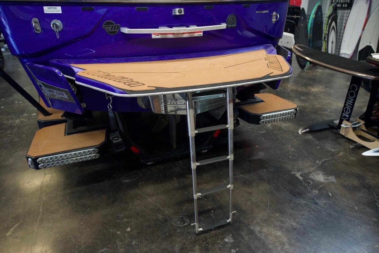 2021 Malibu M220 boat rear view with swim platform and ladder in showroom.