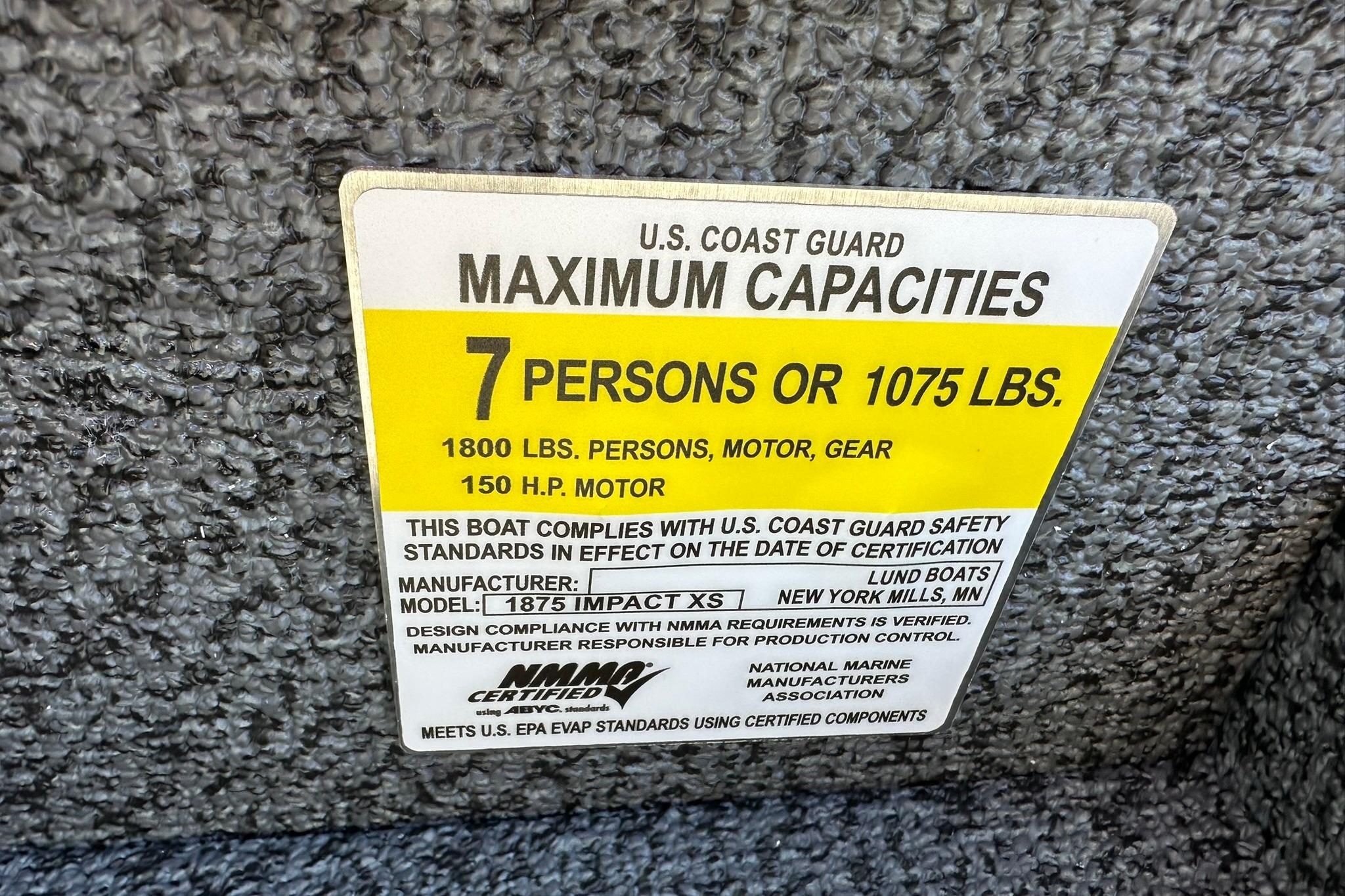 Capacity label for 2026 Lund 1875 Impact XS Sport, 7 persons or 1075 lbs.