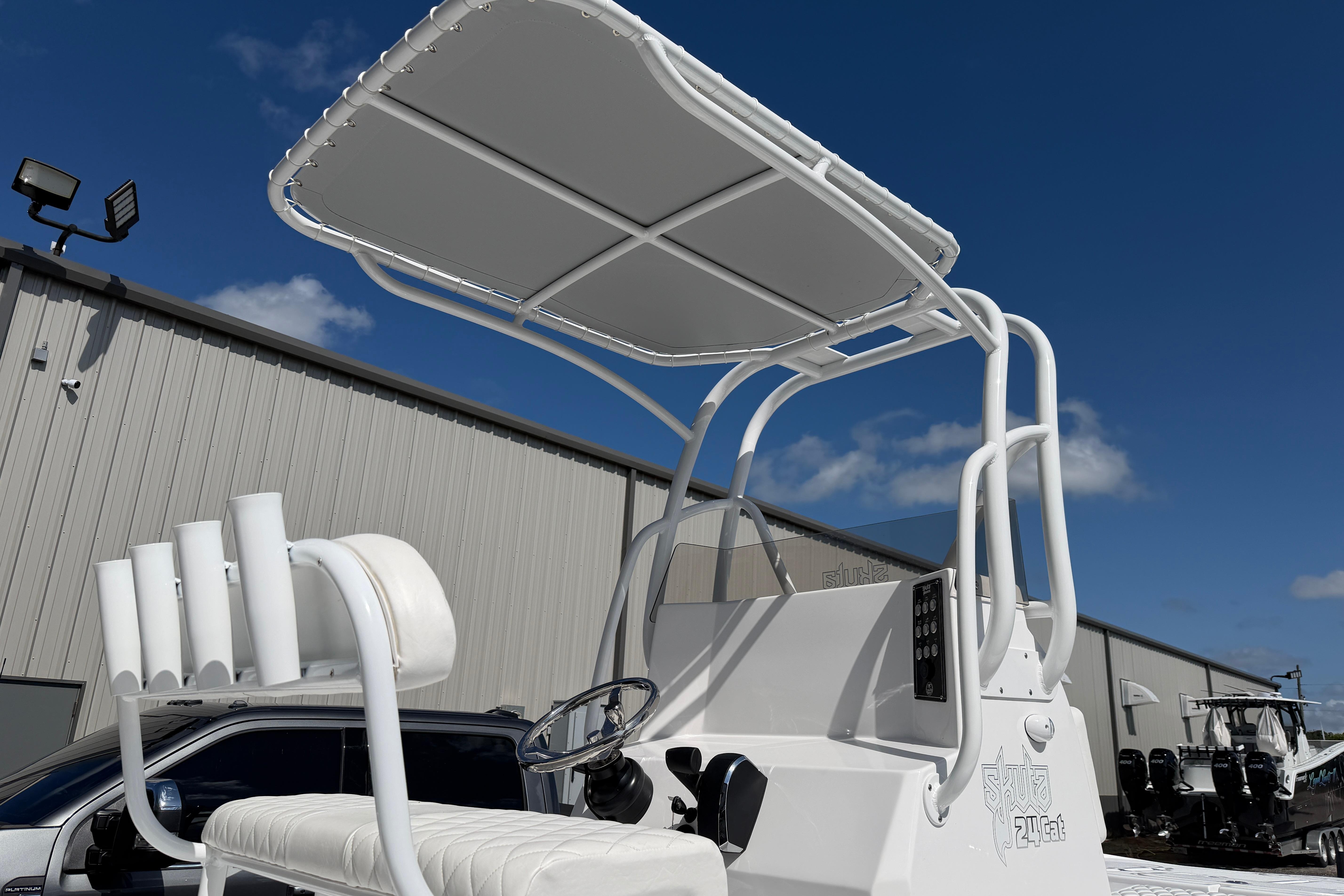 2026 Skuta 24 Cat boat with canopy and seating, displayed outdoors.
