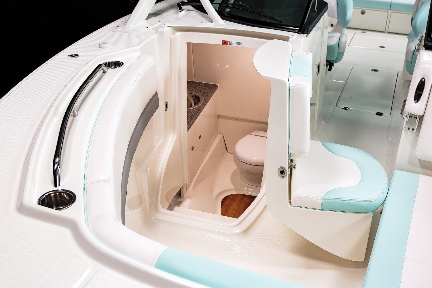 Manufacturer Provided Image: 2025 Robalo R317 Dual Console boat interior with compact bathroom and seating.