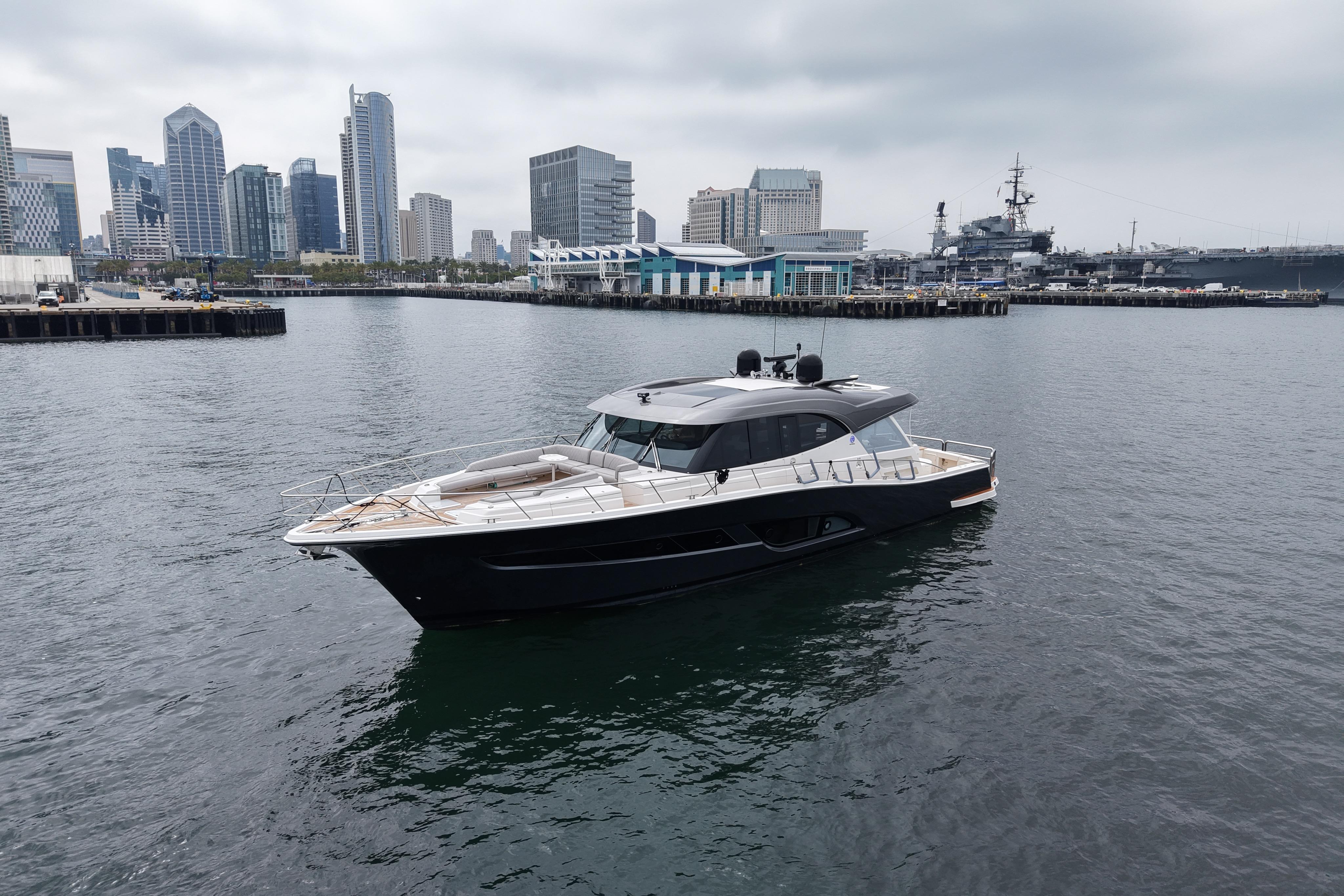2023 Riviera 645 SUV yacht in urban harbor with city skyline backdrop.