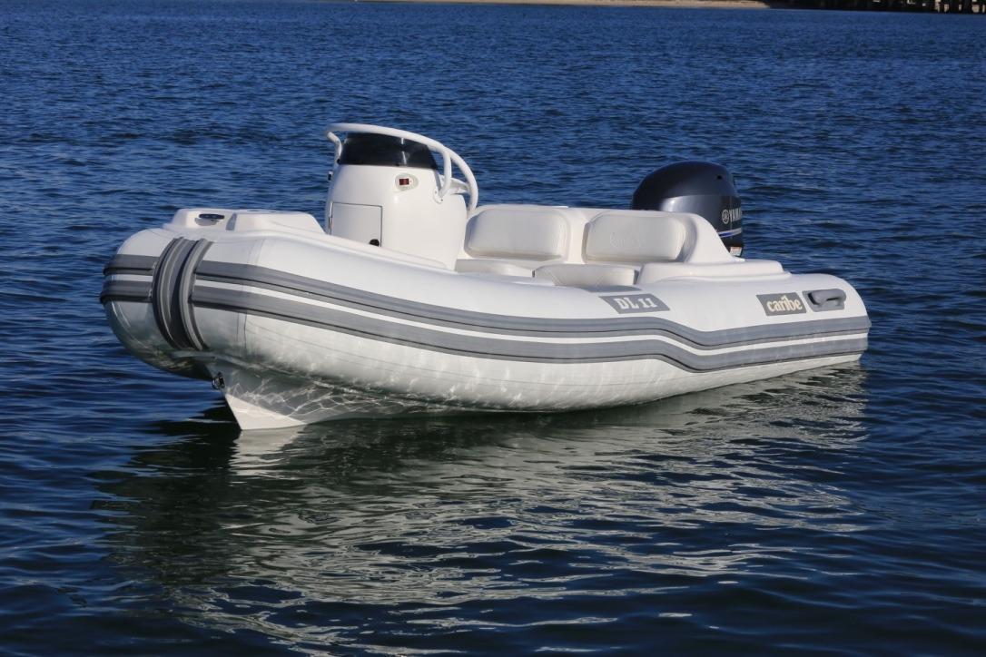 2025 Caribe DL11 inflatable boat on calm water, featuring sleek design and modern outboard motor.