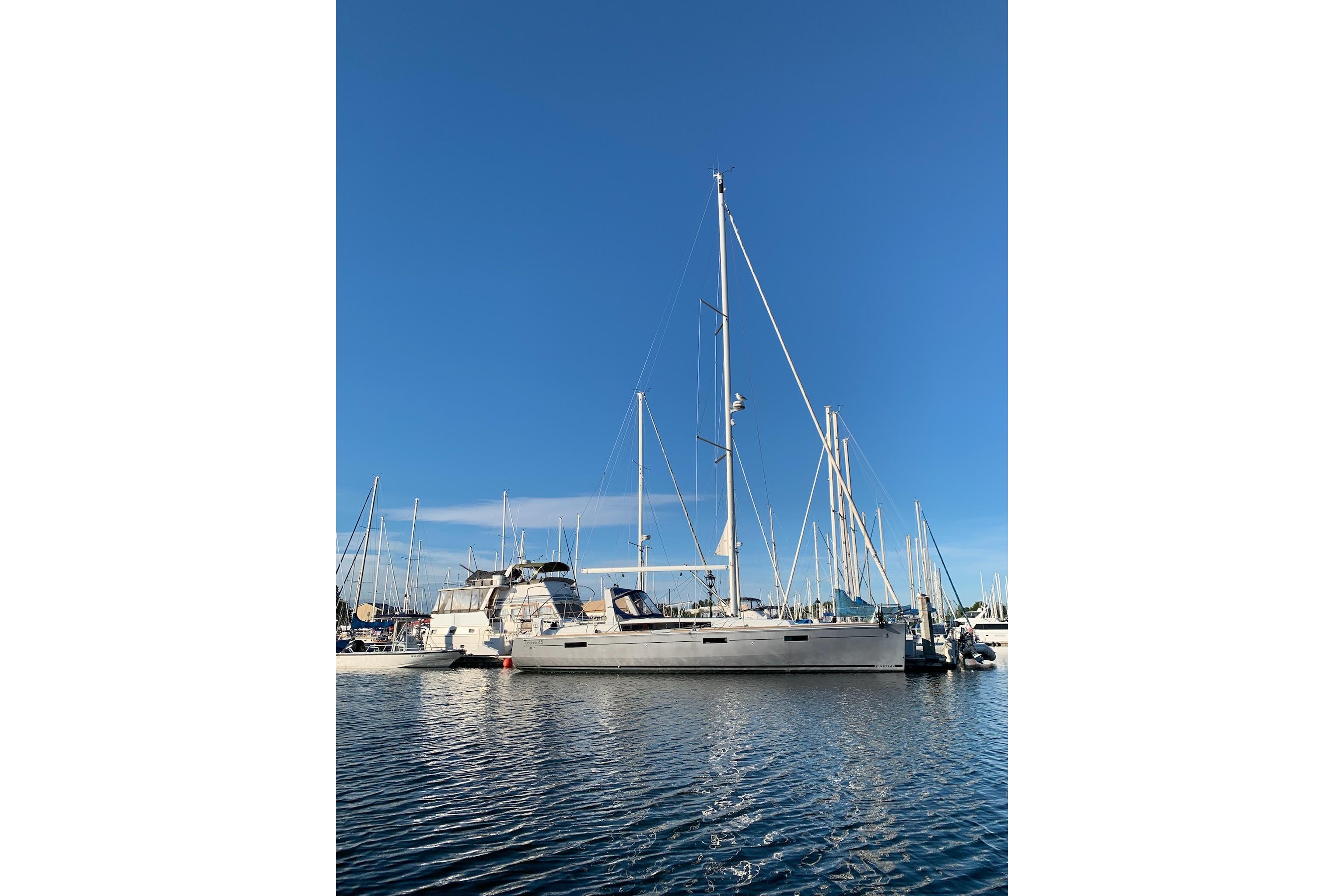 2018 Beneteau Oceanis 45 sailboat docked in a marina under clear blue skies.