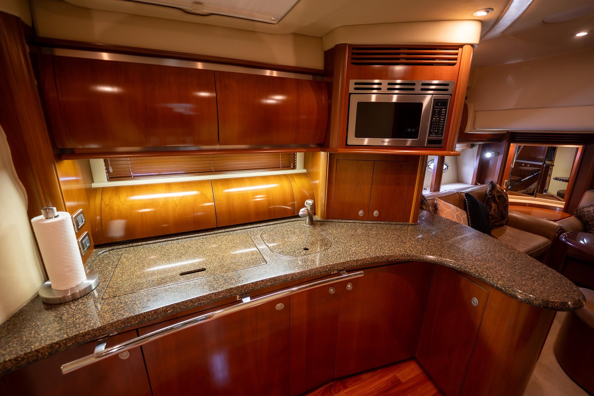 Luxurious kitchen interior of 2005 Sea Ray 500 Sundancer yacht with wood cabinetry and modern appliances.
