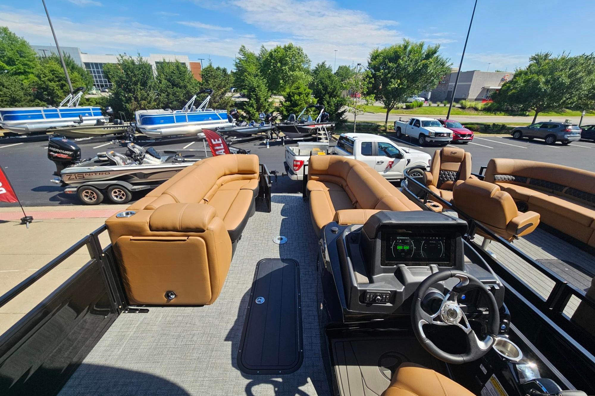 2026 Regency 230 DL pontoon boat with tan seating, parked in a dealership lot.