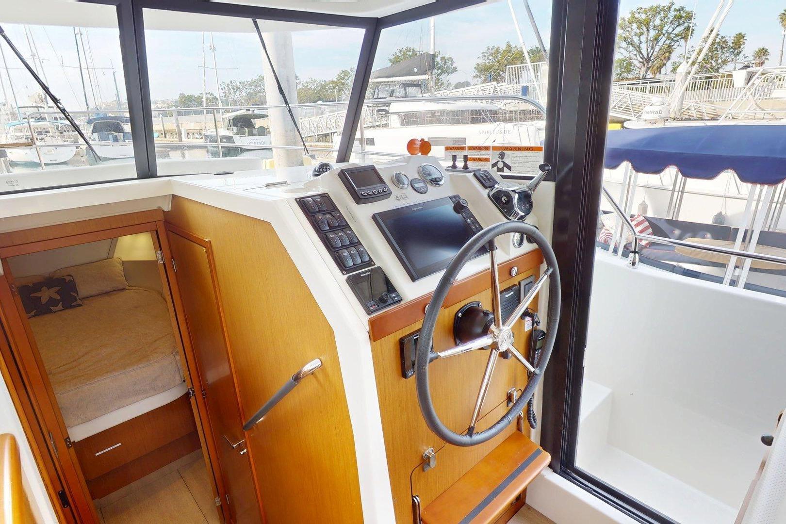 2021 Beneteau Swift Trawler 35 helm station with steering wheel and cabin view.