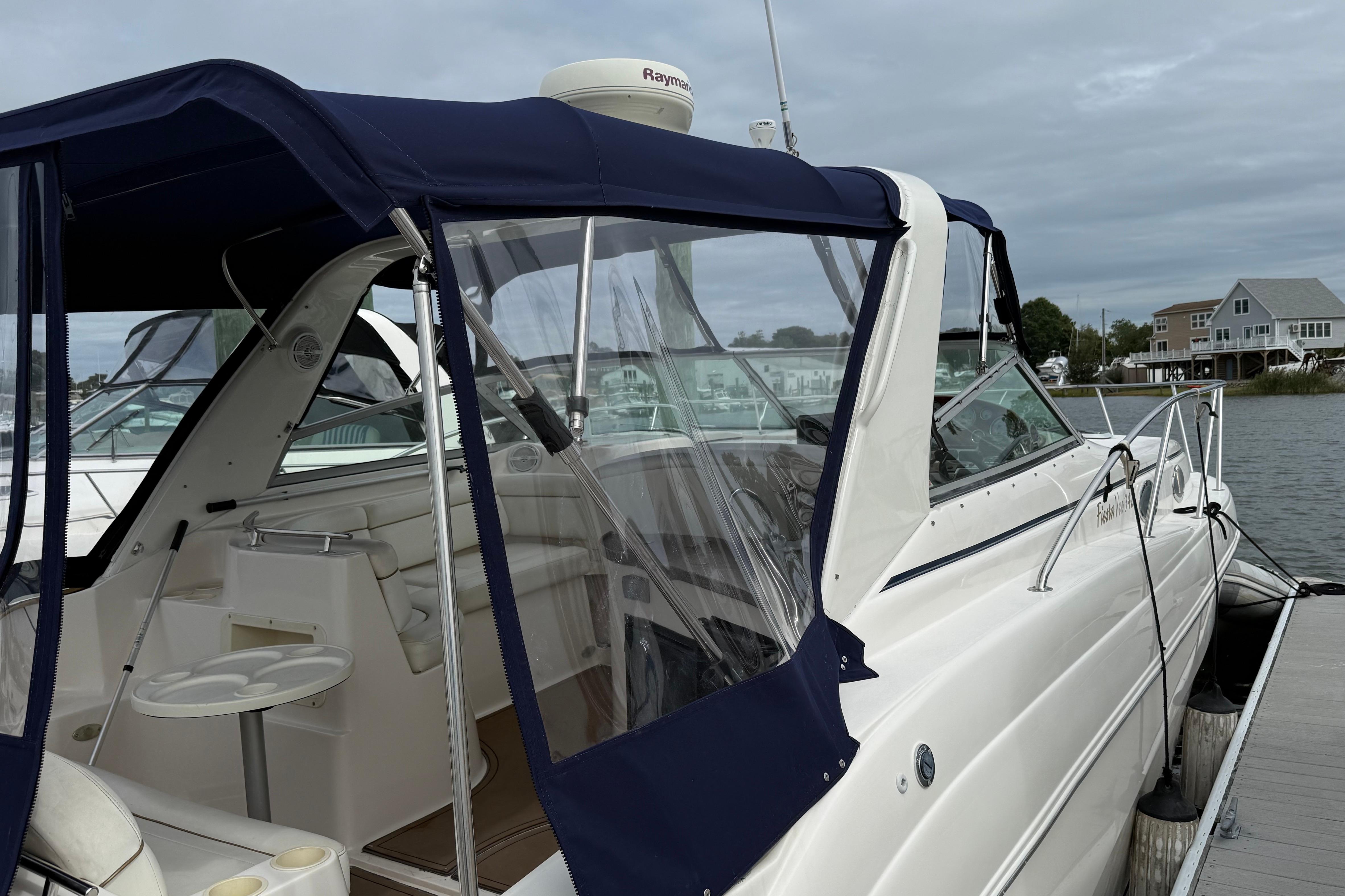 2004 Rinker 342 boat docked, featuring a blue canopy and spacious interior seating.
